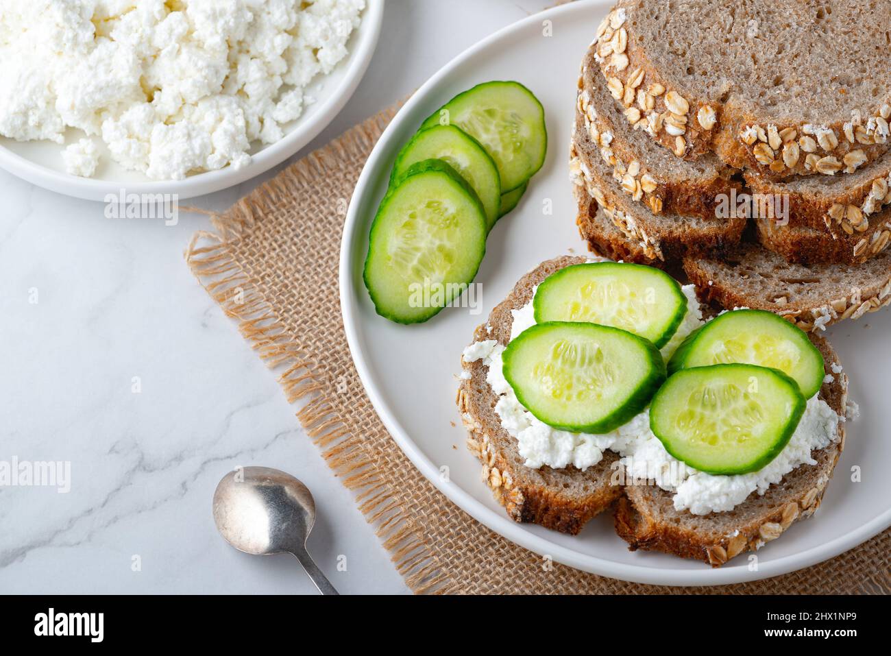 Fette di pane di segale con formaggio casereccio e cetrioli su sfondo bianco Foto Stock