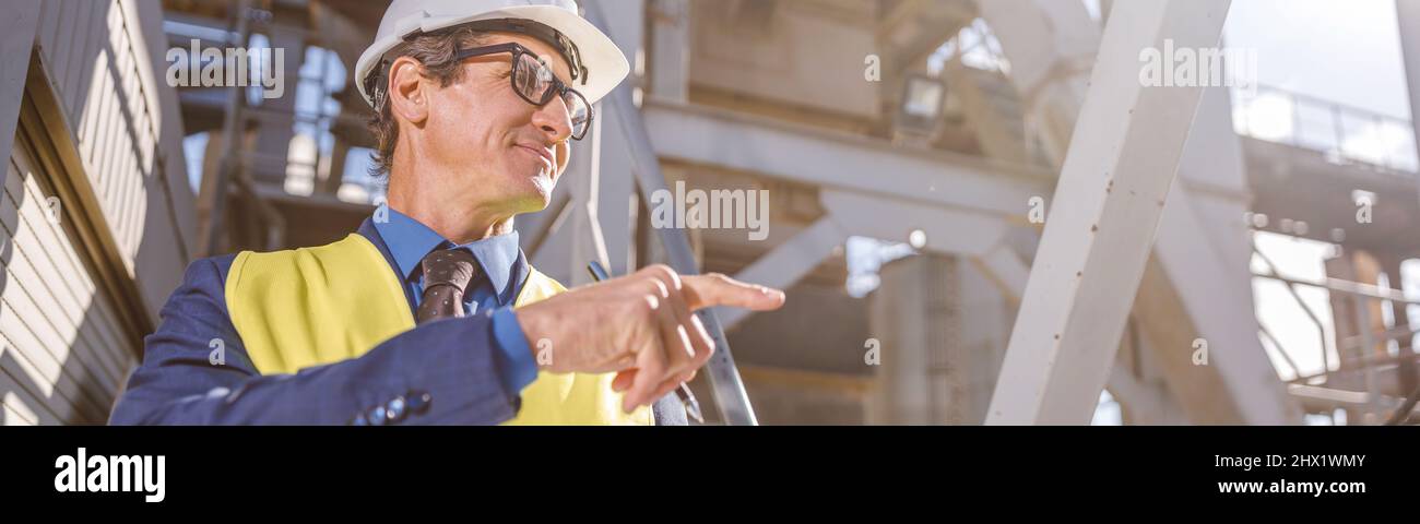Ingegnere maschile con documenti che indicano qualcosa in fabbrica Foto Stock