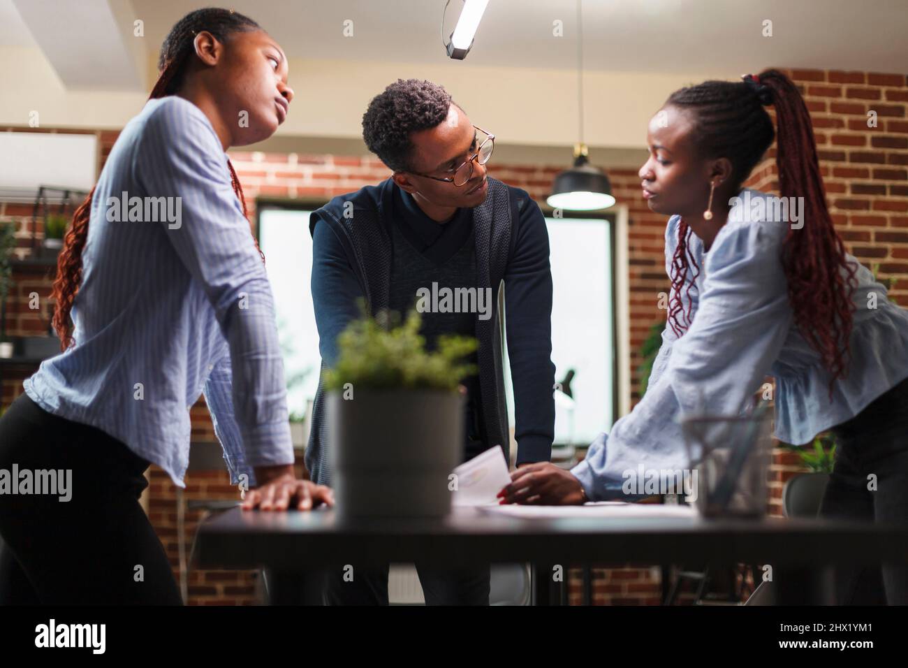 I colleghi della società di affari afro-americana nell'incontro circa lo stato finanziario di progetto di startup. I membri del team delle agenzie di marketing esaminano la documentazione contabile e i dati statistici sui ricavi. Foto Stock