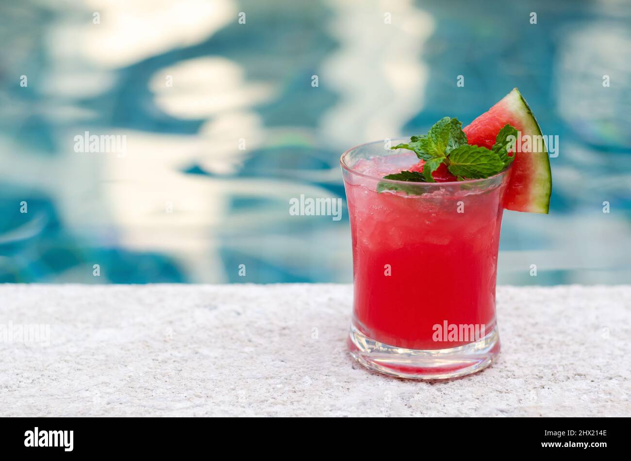 Un bicchiere di frullato di cocomero si trova accanto alla piscina per un drink estivo. Foto Stock