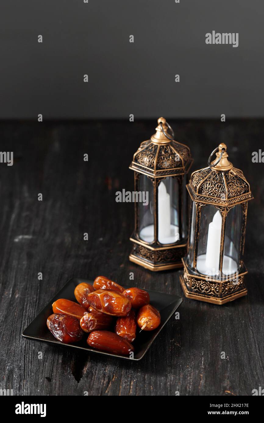 Lanterna di fuoco selezionata e date su tavola di legno. Concetto di festa di Ramadan kareem, spazio di copia per il testo. Focus su frutta datteri Foto Stock