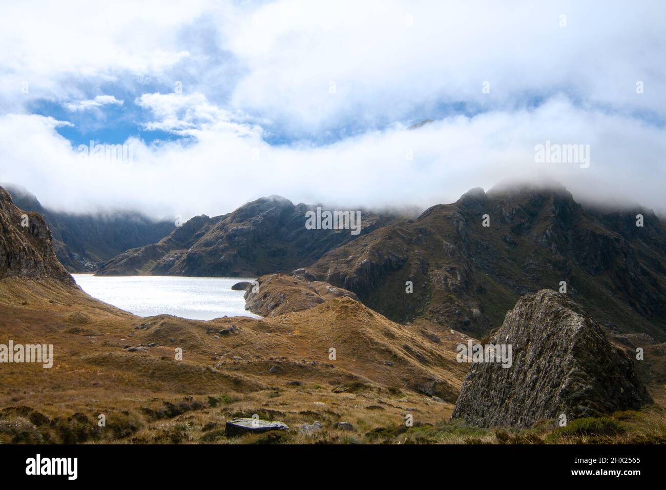 Paesaggio di montagne nuvolose e lago Harris, Alpi meridionali, Routeburn Track Harris Saddle, Nuova Zelanda Foto Stock