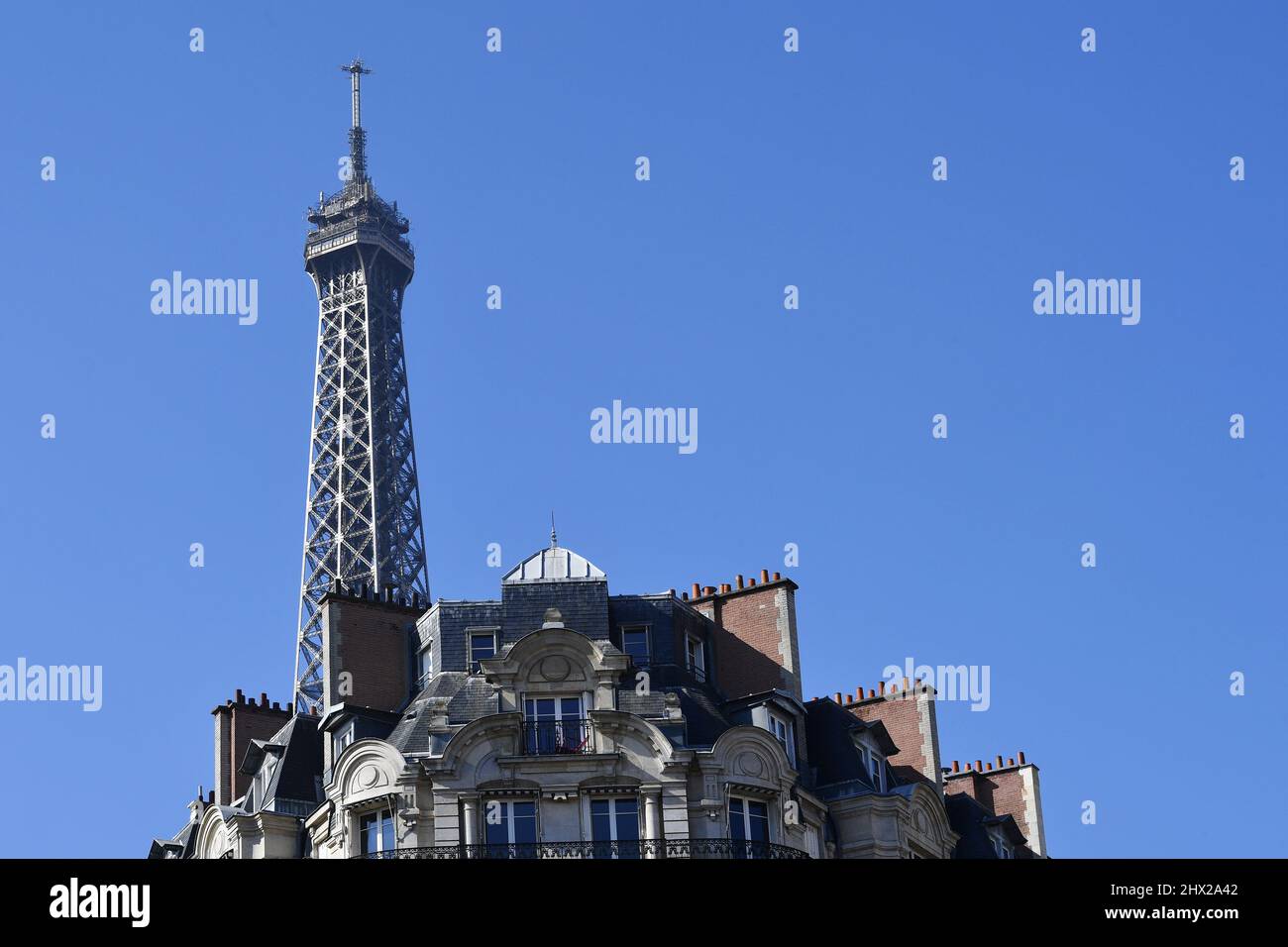 la Torre Eiffel che si erge direttamente sopra un classico edificio residenziale parigino in stile Haussmann lungo l'Avenue de la Bourdonnais nel 7° arrondissement Foto Stock