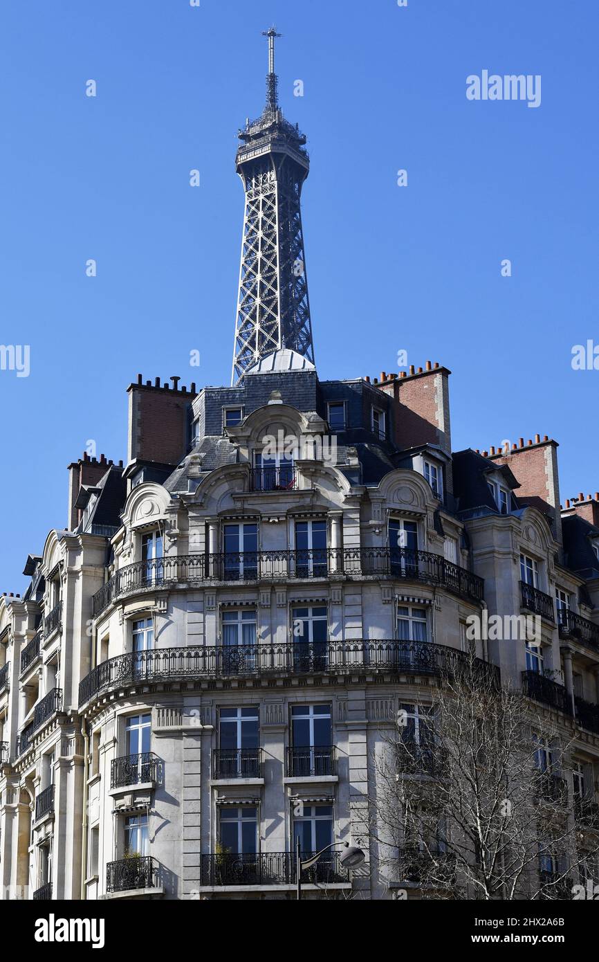 la Torre Eiffel che si erge direttamente sopra un classico edificio residenziale parigino in stile Haussmann lungo l'Avenue de la Bourdonnais nel 7° arrondissement Foto Stock