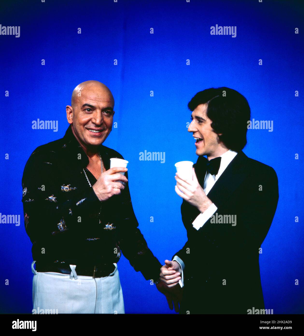 Telly Savalas, amerikanischer Schauspieler, Titel-Darsteller in der Krimi-Serie Kojak, zu Gast im ZDF, Musiksendung disco, 1975, hier bei einem Sketch mit disco Moderator Ilja Richter. Telly Savalas, attore americano, titolo personaggio nella serie di crimine Kojak, come ospite nel canale televisivo tedesco ZDF, discoteca show musicale, 1975, qui durante uno schizzo con discoteca presentatore Ilja Richter. Foto Stock