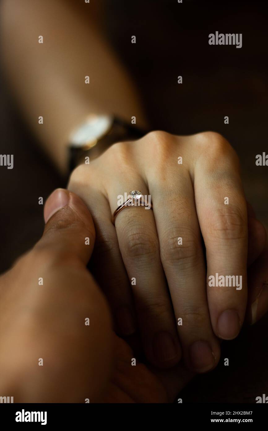 Un uomo che tiene la mano di sua moglie con il suo anello di matrimonio/anello di fidanzamento visibile sul suo cerametto. Foto Stock