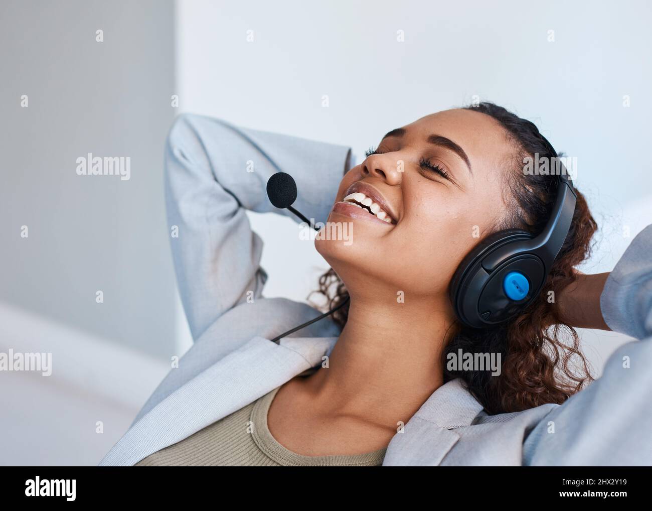 Una giovane donna con cuffia si inclina all'indietro e fa una pausa durante la giornata di lavoro Foto Stock