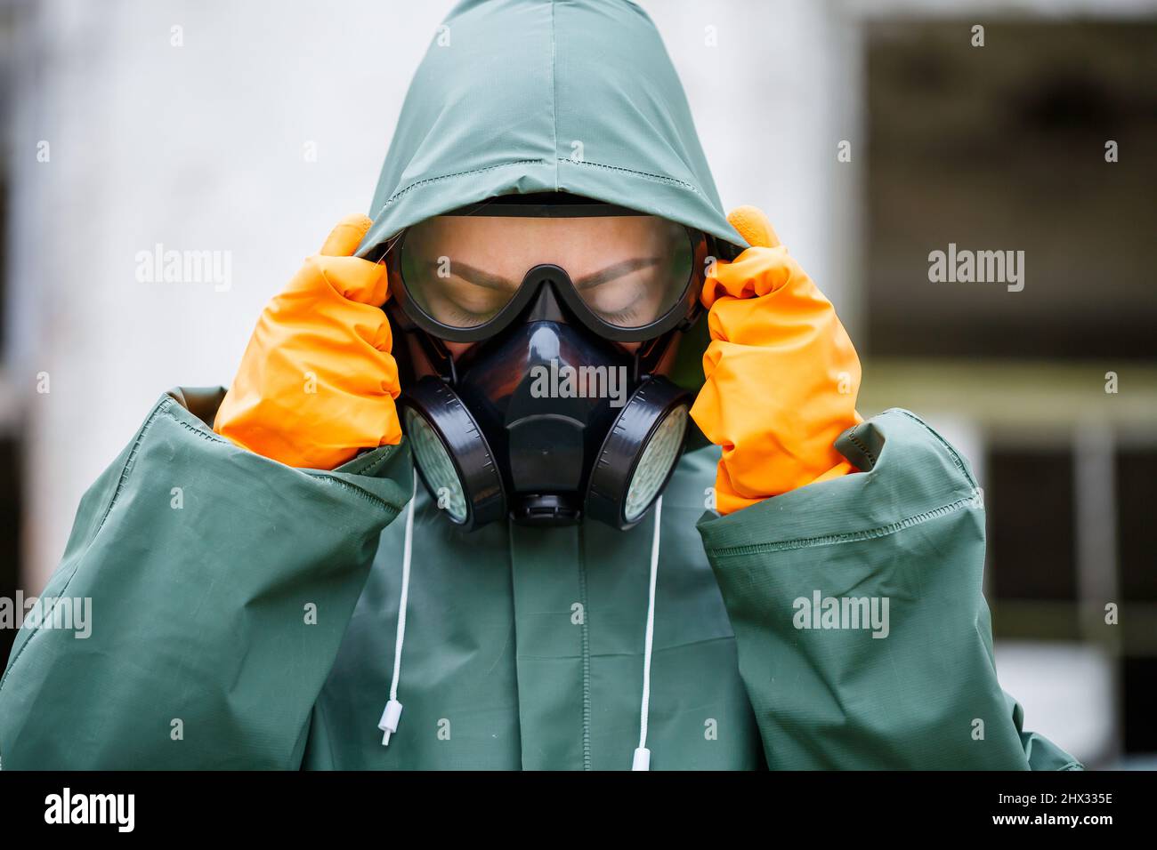 Uno scienziato dosimetristo in indumenti protettivi e una maschera a gas controlla il livello di