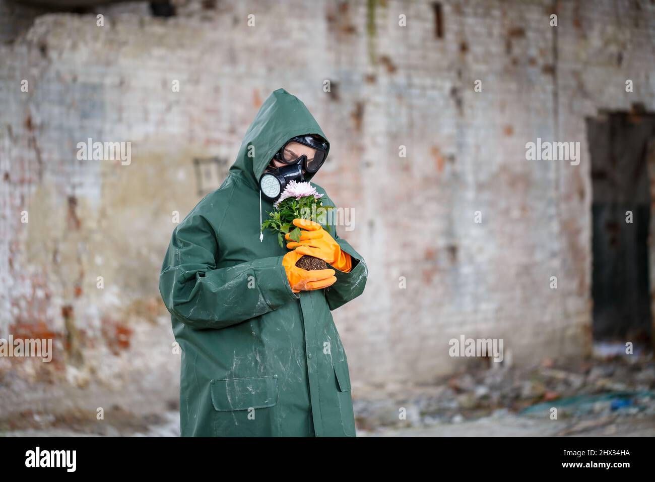 Un ispettore di radiazioni dello scienziato dosimetristo in indumenti protettivi e una maschera a gas esamina la zona di pericolo. Primo piano. Fiore. Catastrofia ecologica Foto Stock