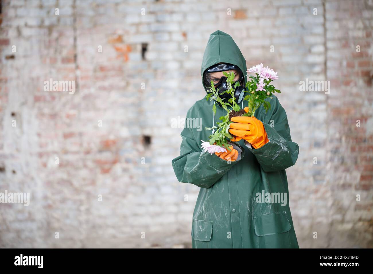 Un ispettore di radiazioni dello scienziato dosimetristo in indumenti protettivi e una maschera a gas esamina la zona di pericolo. Primo piano. Fiore. Catastrofia ecologica Foto Stock