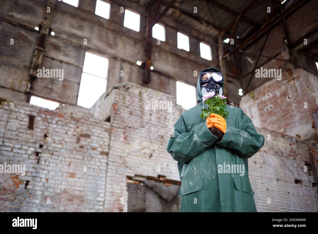 Un ispettore di radiazioni dello scienziato dosimetristo in indumenti protettivi e una maschera a gas esamina la zona di pericolo. Primo piano. Fiore. Catastrofia ecologica Foto Stock