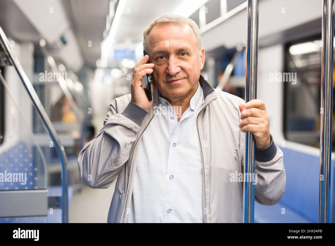Uomo maturo che parla al telefono in macchina della metropolitana Foto Stock