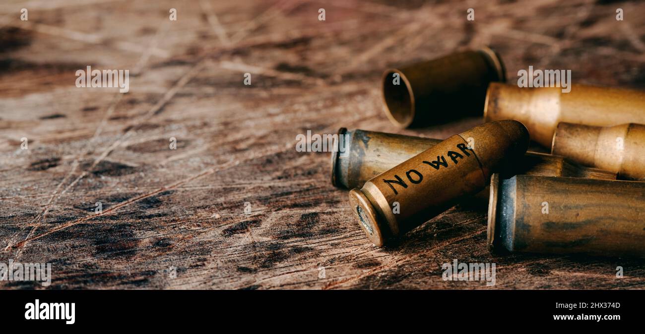 il testo no war scritto in un proiettile su una pila di proiettili su una superficie rustica, in un formato panoramico da utilizzare come banner web o intestazione Foto Stock