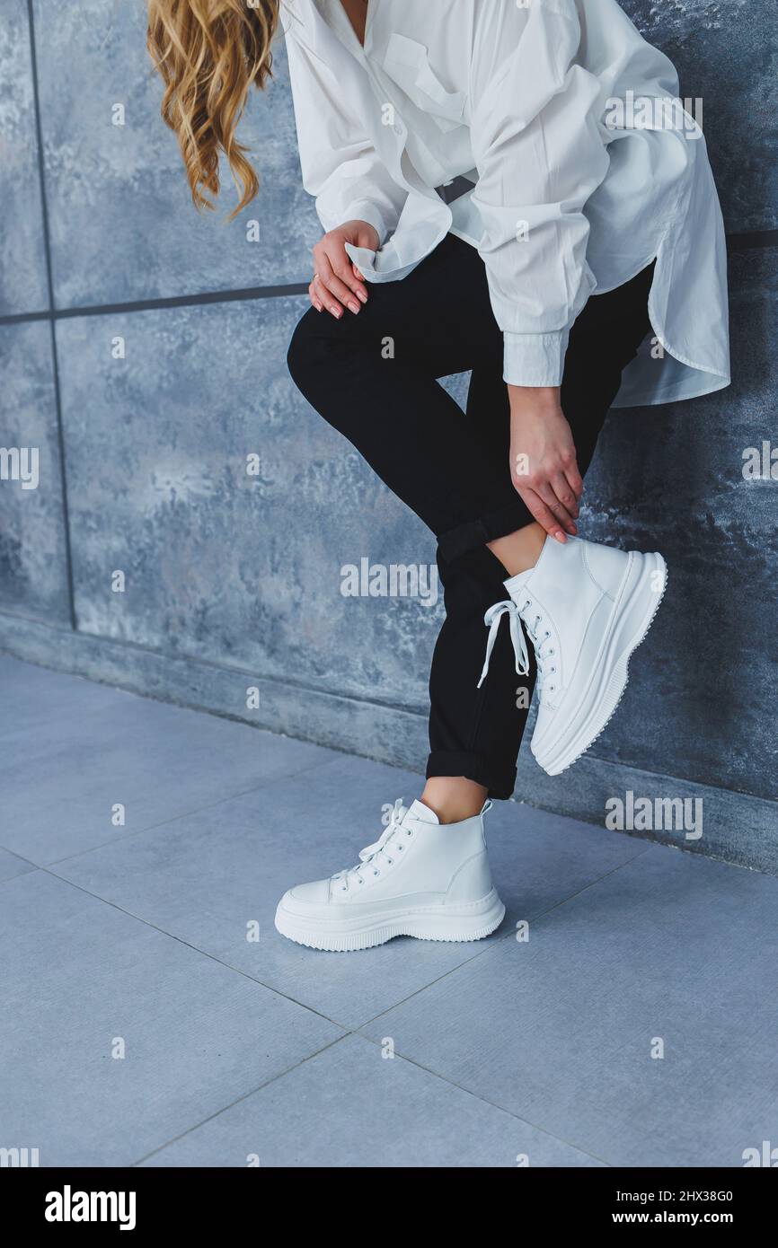 Gambe da donna in pantaloni neri e sneaker in pelle bianca. Moderno stile  informale. Nuova collezione di scarpe Foto stock - Alamy