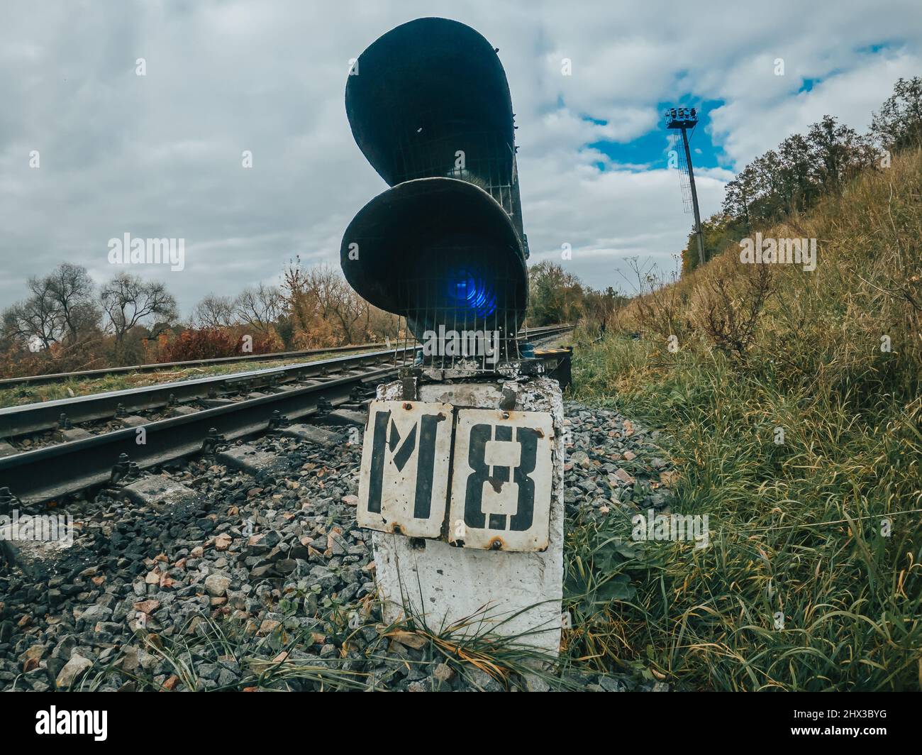 Dispositivo di segnalazione o segnale a semaforo sulla ferrovia. Svolta del binario ferroviario. Rotaie di ferro in campagna. Foto Stock