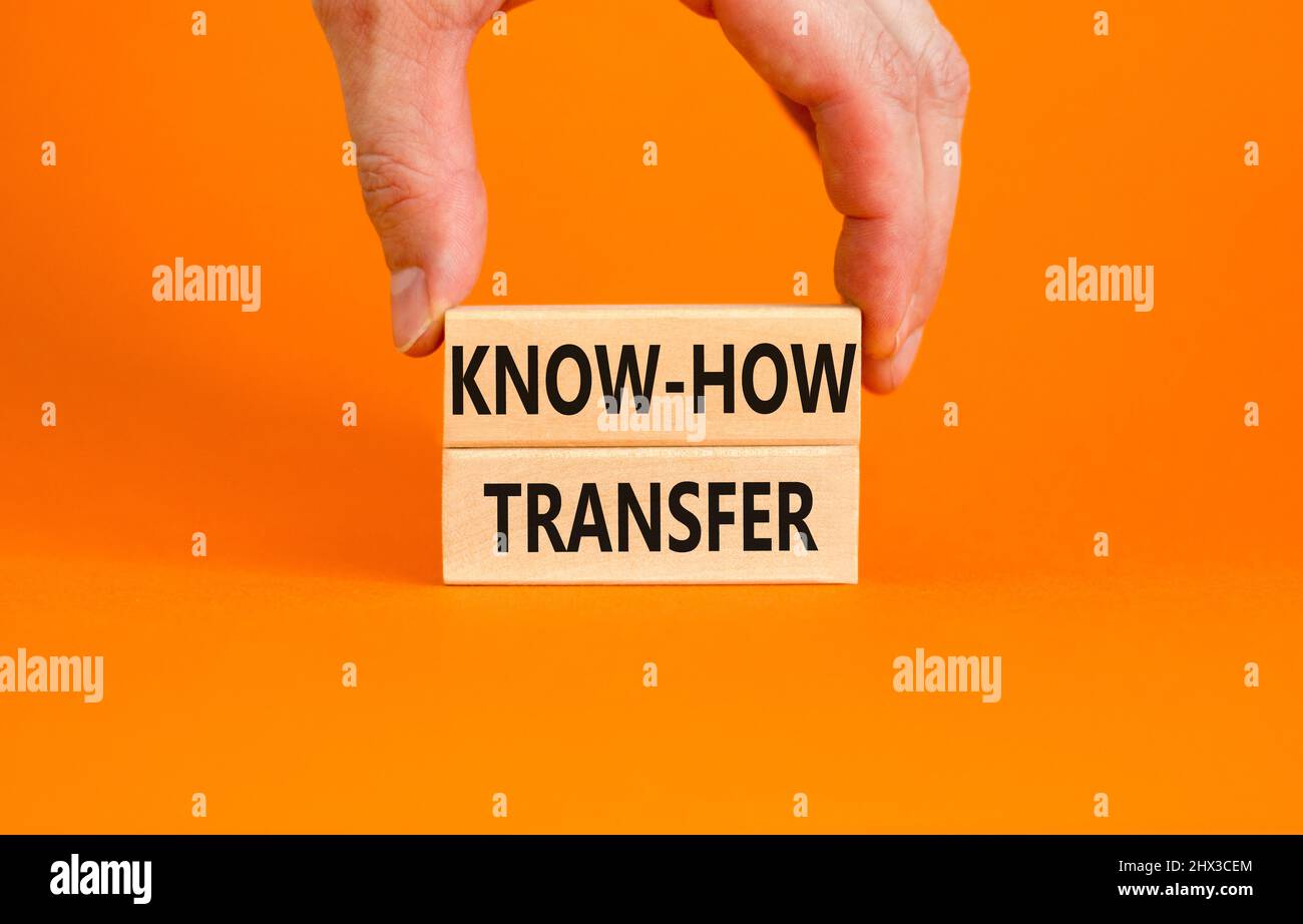 Simbolo di trasferimento del know-how. Concetto parole know-how trasferimento su blocchi di legno su bello arancione tavolo sfondo arancione. Mano dell'uomo d'affari. Spazio di copia. Foto Stock