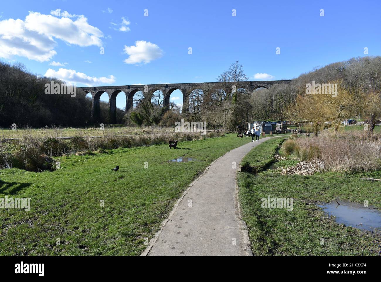 Persone che camminano nel parco di Porthkerry di fronte al viadotto ferroviario, Barry, Glamorgan, Galles Foto Stock