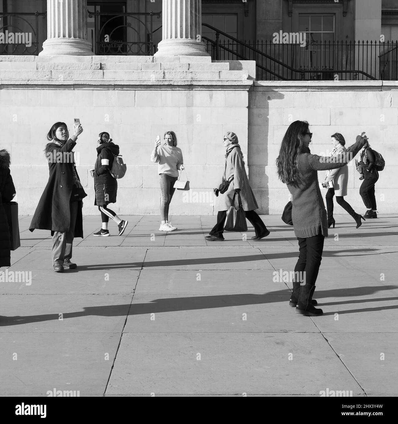 Londra, Greater London, Inghilterra Marzo 08 2022: Donna che passa davanti alla National Gallery diversi autofoni in occasione della Giornata Internazionale delle Donne. Foto Stock