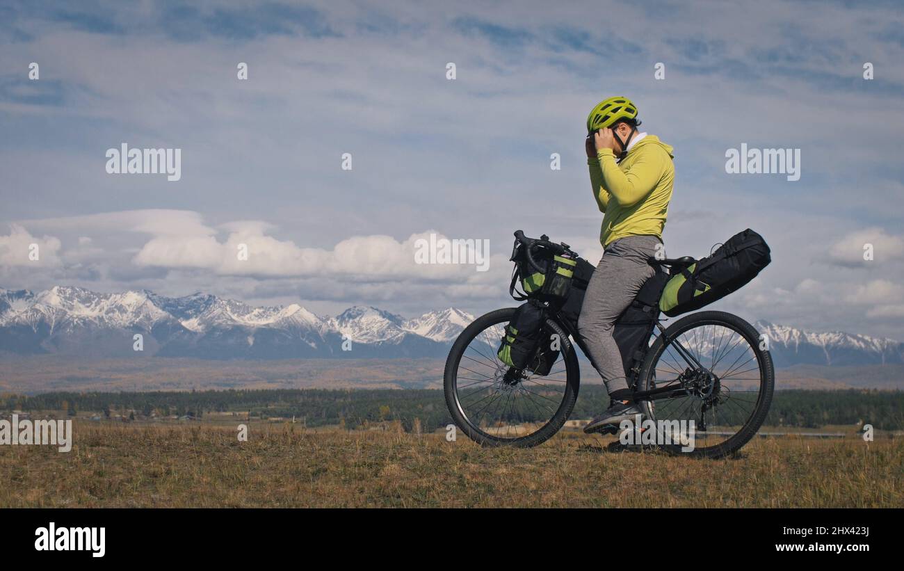 L'uomo viaggia su percorsi ciclabili misti con bikepacking. Il viaggio del  viaggiatore con le borse della bicicletta. Sport turismo bikepacking, bici,  abbigliamento sportivo in verde nero. Montagna innevata Foto stock - Alamy