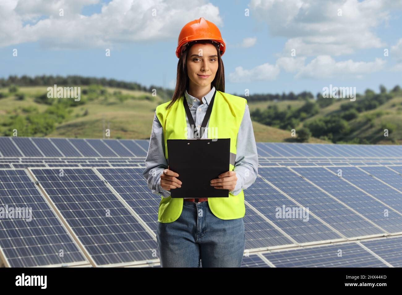 Ingegnere femminile che tiene una clipboard su un campo verde stazione solare fotovoltaica Foto Stock