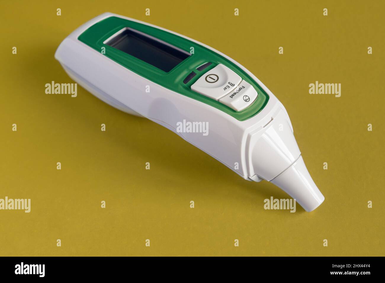 Termometro a infrarossi per fronte e orecchio per bambino, adulto, ospedale con allarme di febbre isolato dipinto di verde su sfondo colorato studio. Oggetto e cibo Foto Stock