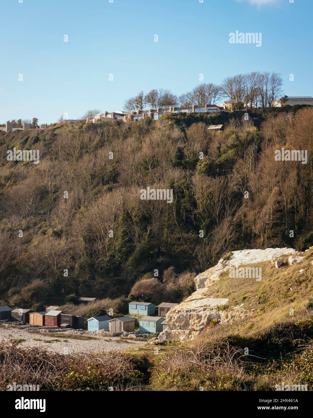 Vista degli alloggi dal basso, con le vegetazioni sulla scogliera e i piccoli capannoni sul fondo della strada calcarea. Clifftops, Dorset, Portland, U. Foto Stock