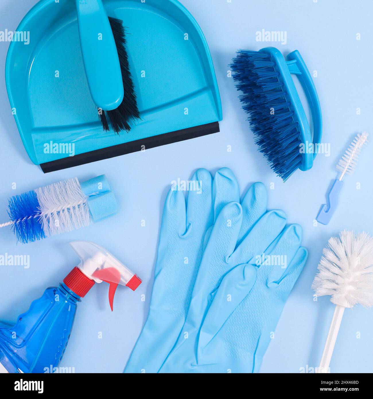 Sfondo blu pastello con strumenti di pulizia per lavori domestici. Disposizione piatta Foto Stock