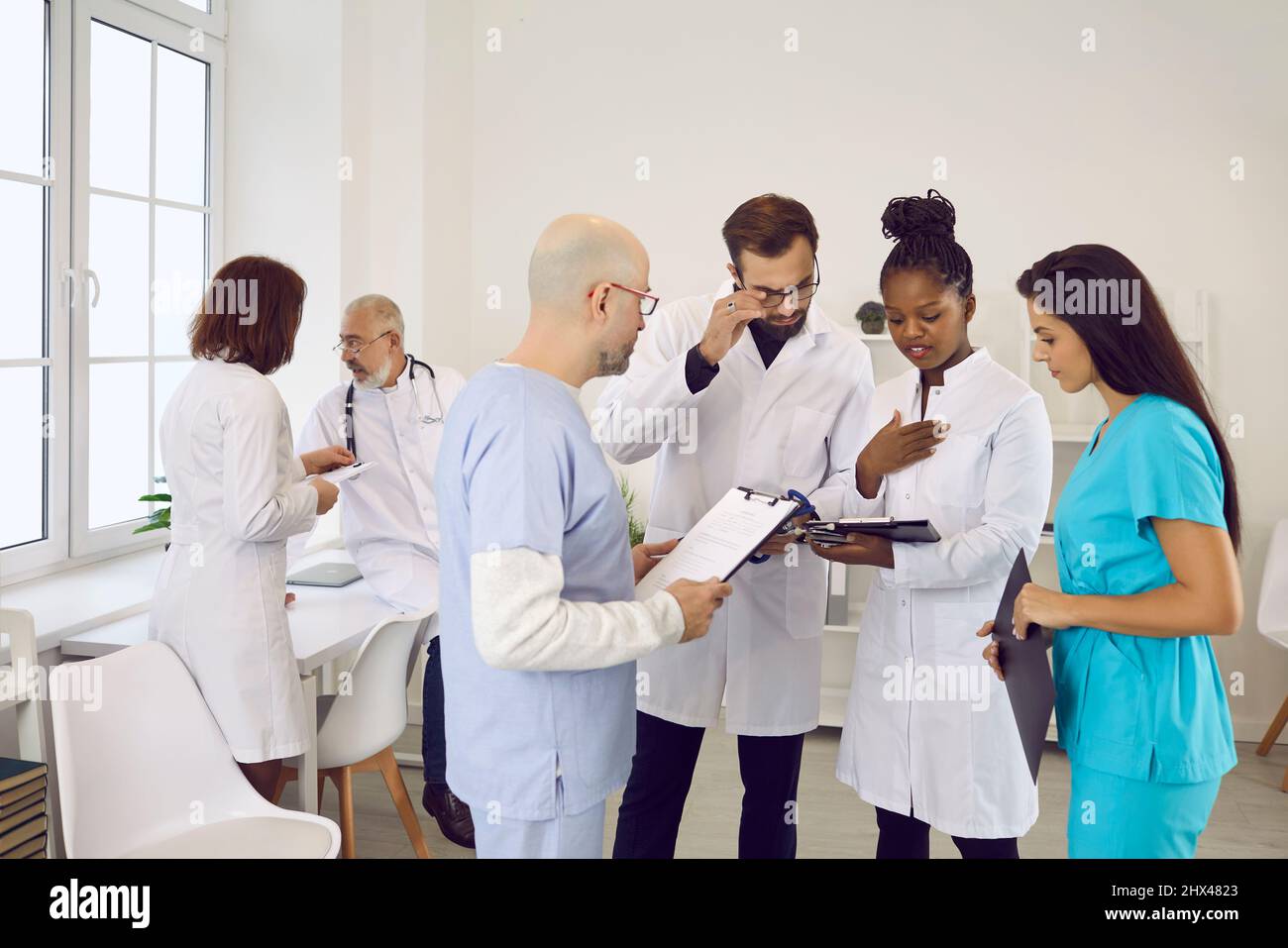 Gruppo di medici e infermieri nella sala del personale ospedaliero che discutono insieme di qualcosa Foto Stock