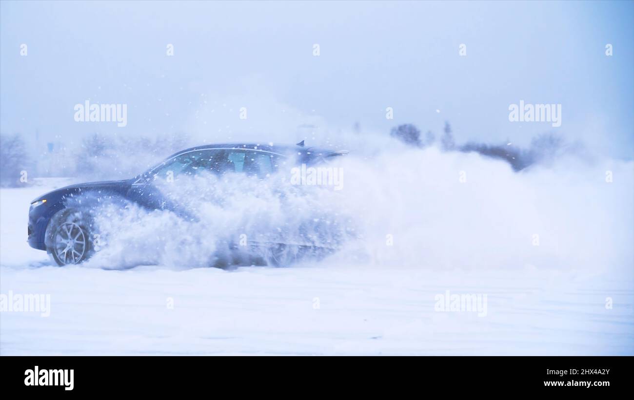 Auto che fa inversione a U nella neve. Le auto sportive guidano nella neve. Il crossover blu fa trucchi nella neve. Foto Stock