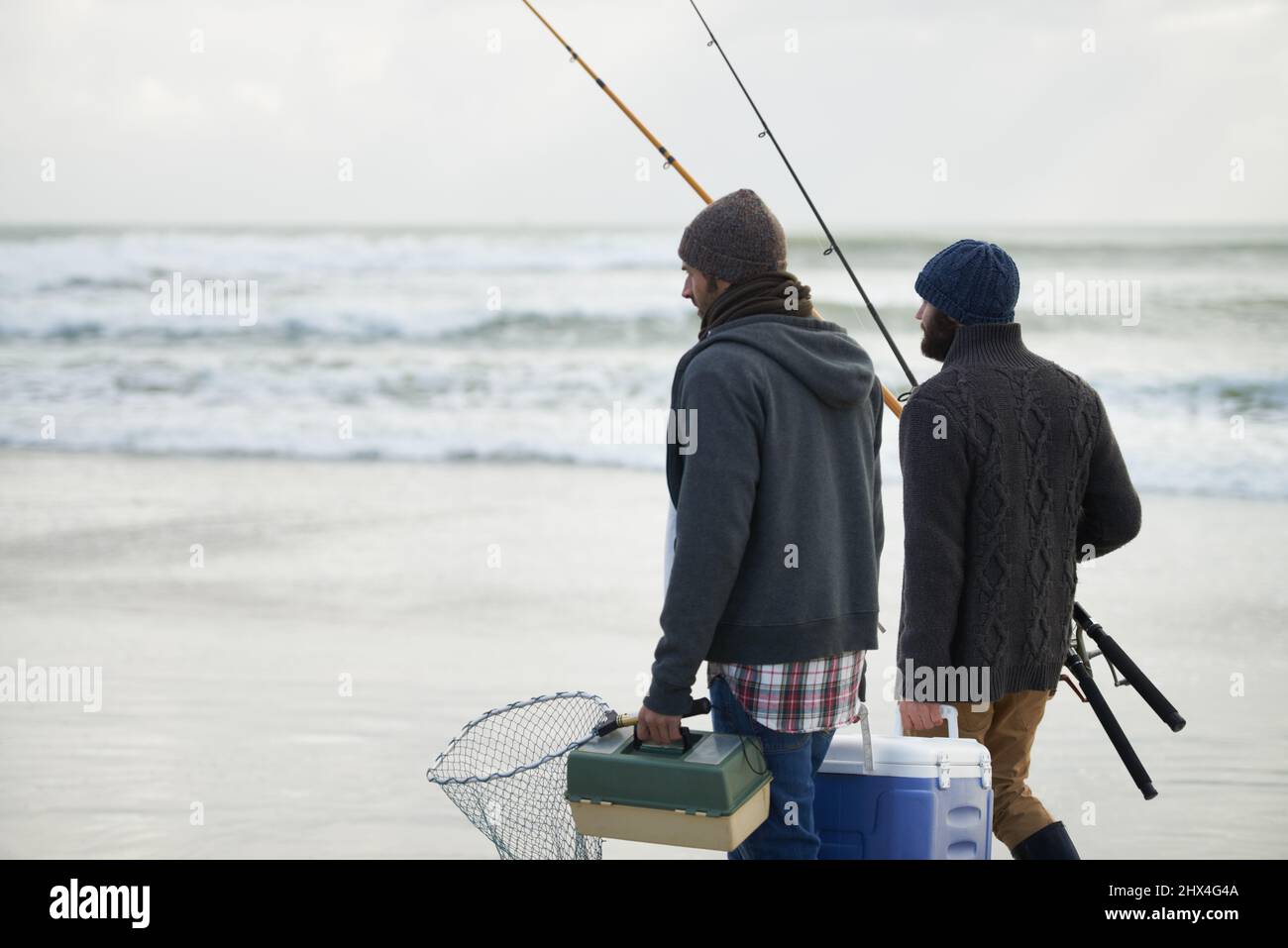 Confezionato e pronto a pescare. Scatto di due amici che pescano in una mattina presto coperto. Foto Stock