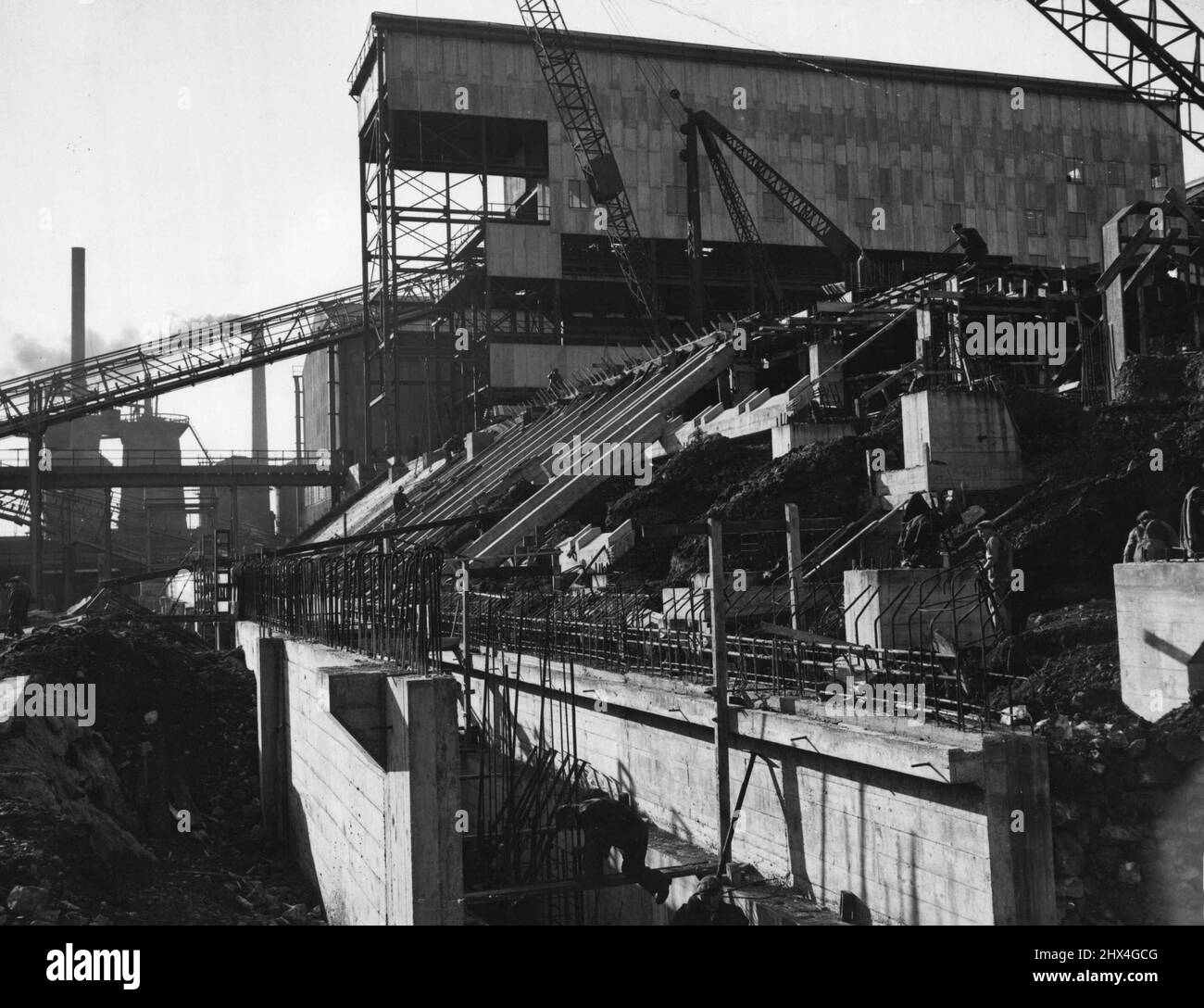 Via d'uscita dei progetti di capitale della Gran Bretagna -- l'industria britannica, che lotta per coprire con le esportazioni aumentate il gap causato dalla guerra nell'economia nazionale, è impegnata in un vasto programma di espansione di capitale. Il potere di guadagno britannico deve essere aumentato; ed aumentato particolarmente in dollari, poiché una parte importante delle nostre forniture di cibo e di materie prime può essere comprata soltanto con dollari. L'Europa deve essere messa in piedi da sola e la Gran Bretagna deve fare la sua parte anche in questo. La fine dell'assistenza del dollaro E.R.R. nel 1952 stabilisce una scadenza per tutti questi sforzi. Questo impianto di sinterizzazione gigante fa parte di t Foto Stock