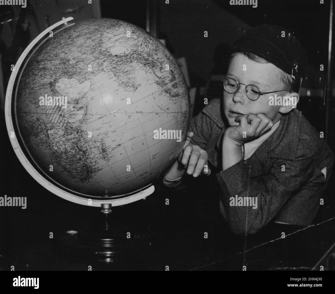 Dove si trova? Perplesso. Anche se Sydney sembra un grande luogo di otto anni John Seymour, di Longueville, ha difficoltà a trovarlo sul globo. Ha fatto shopping per gli uncini della scuola in un negozio della città. Maggio 17, 1950. Foto Stock