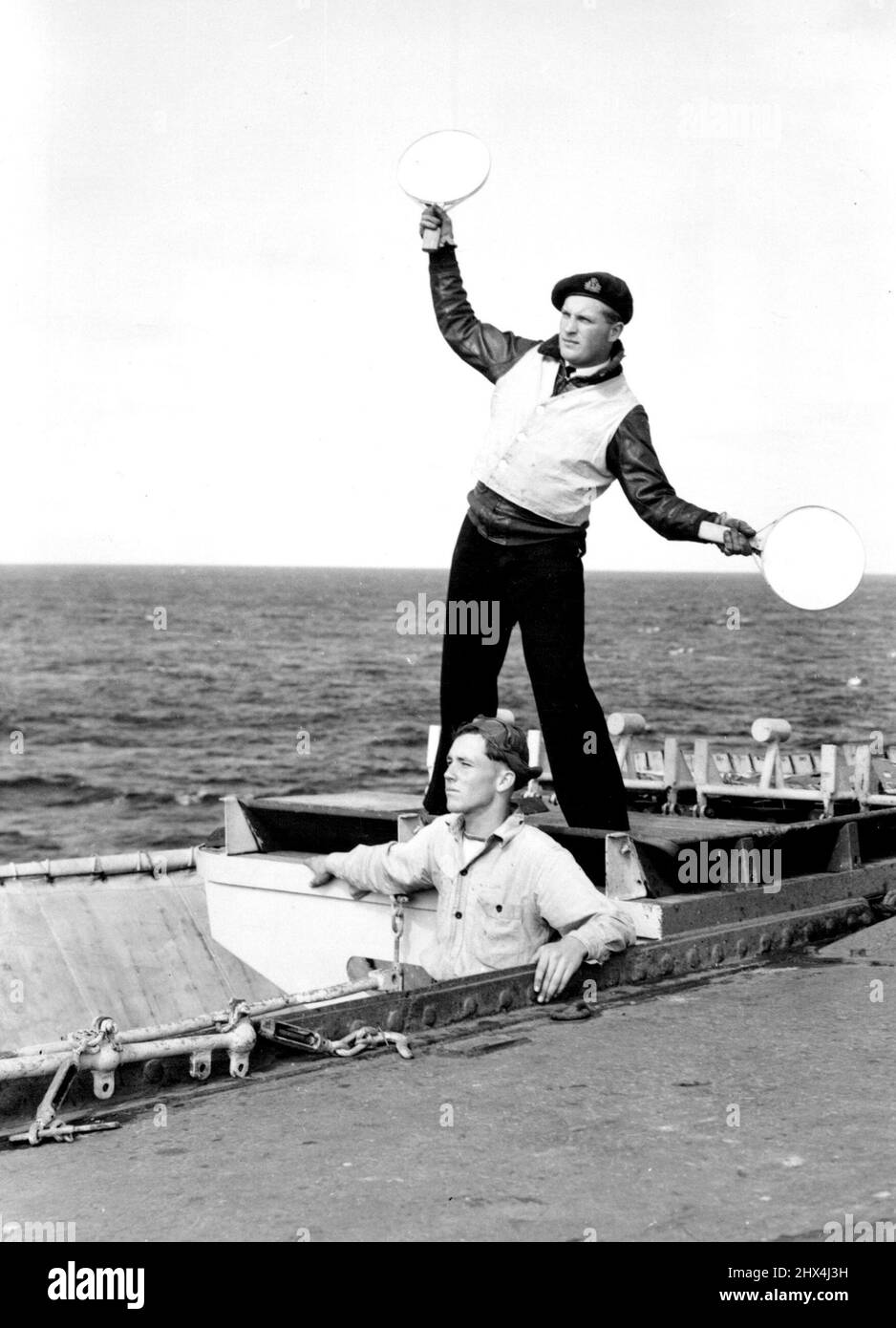 Il tenente J.M.Jones, R.N., ufficiale di controllo dell'atterraggio del ponte, fornisce il segnale di 'turn-out' ad un aeromobile. Luglio 31, 1950. (Foto della N.Z. Herald). Foto Stock