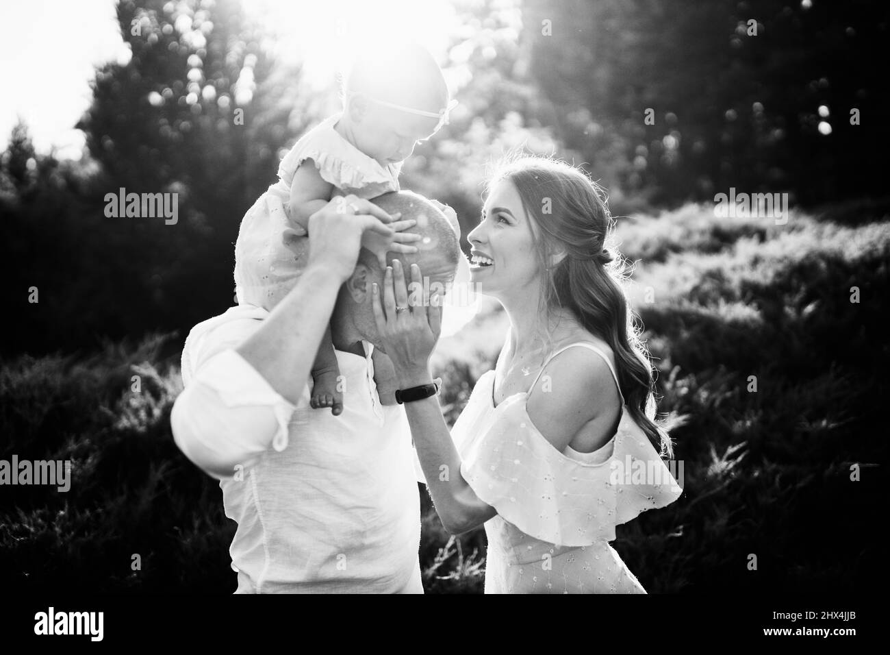 Bella famiglia con adorabile figlia al parco, sorridente, carino toddler seduto sulla spalla dei padri, madre amorevole guardando tenero bambino ragazza, famiglia Foto Stock