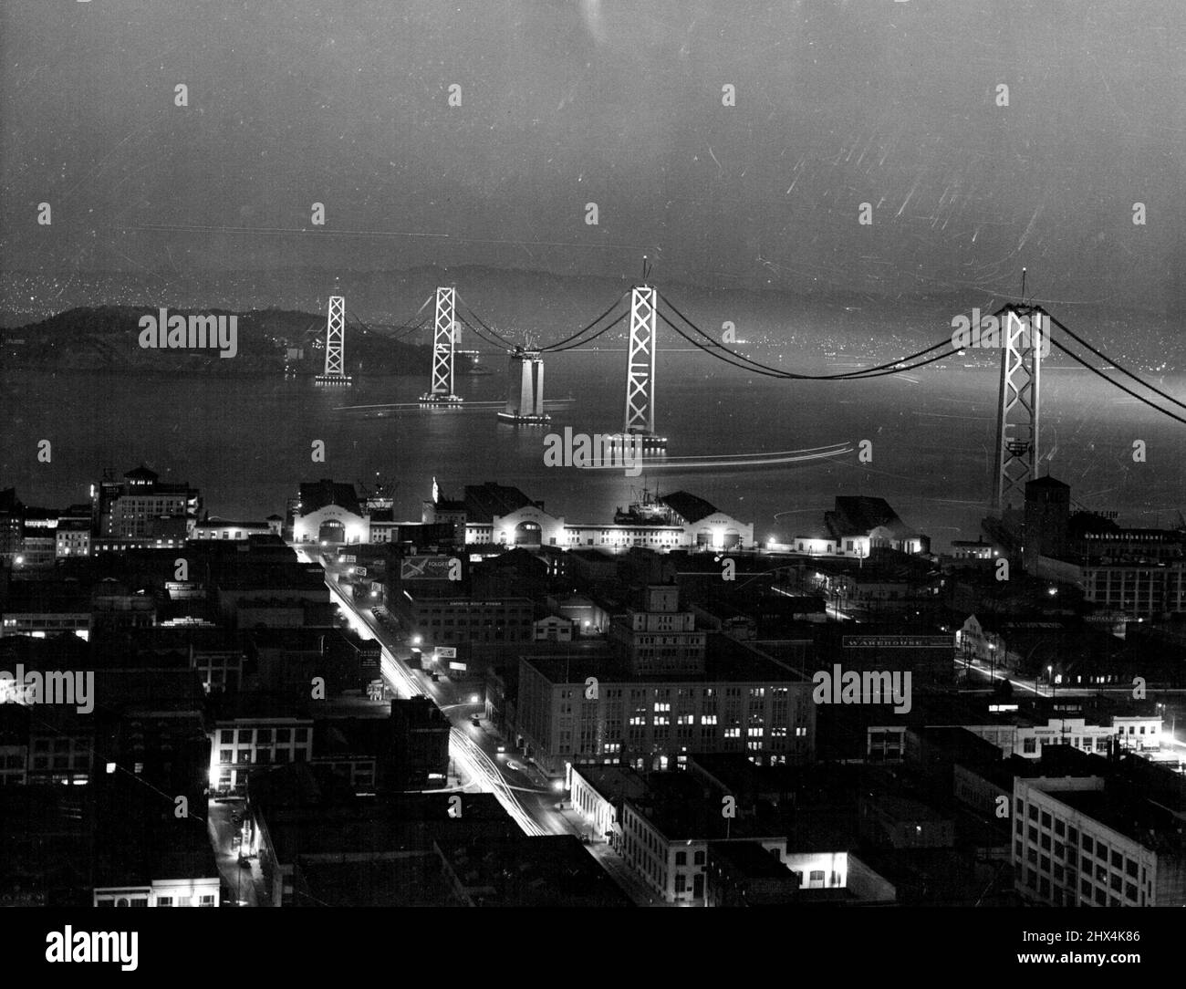 Gruppi illuminati Span San Francisco Bay -- San Francisco-Night e le luci scintillanti che permettono di lavorare 24 ore al giorno sulle passerelle del San Francisco -Oakland Bay Bridge presentano una scena contrastante di bellezza. Le bande più leggere si estendono attraverso l'acqua dal lungomare all'isola di Yerba Buena nella baia. Novembre 19, 1935. (Foto di stampa associata). Foto Stock