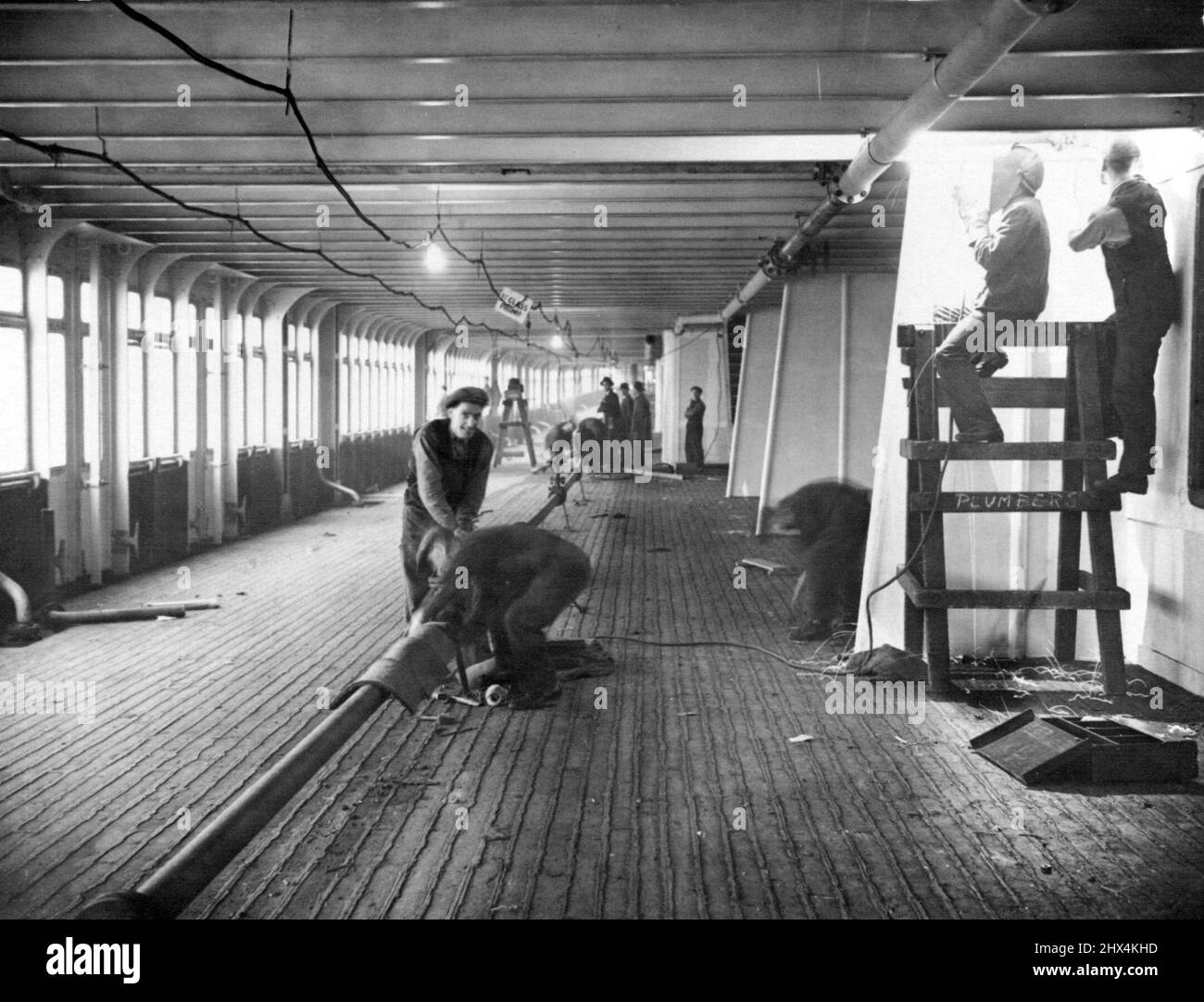 Linea gigante 'Queen-Mary' nearing Completion -- Una vista del ponte 1st Class Promenade, con operai e saldatori occupati al lavoro. Il nuovo colosso britannico, la "Regina Maria", che ora è in fase di completamento a Clydebank, si presenterà il suo primo viaggio il 27th maggio da Southampton e Cherbourg per New York. Dicembre 30, 1935. (Foto di International Graphic Press Ltd.). Foto Stock