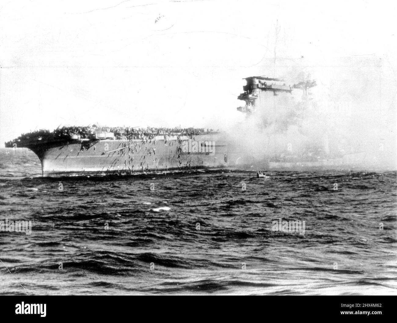 La " immagine della guerra " raggiunse oggi Sydney. Mostra gli uomini della portaerei statunitense Lexington che vanno oltre il lato su corde quando ha preso fuoco dopo la battaglia del Mare di Coral. Mostra i ponti della nave colpita affollata di uomini, mentre altri clampano giù le corde.causa dei ponti la perdita di Carrier era esplosione dei suoi serbatoi di benzina. I suoi ufficiali principali scesero con lei, ma il 92 per cento. Dell'equipaggio sono stati salvati. Lo sterno di un cacciatorpediniere che raccoglie gli uomini può essere visto a destra. Luglio 21, 1942. Foto Stock