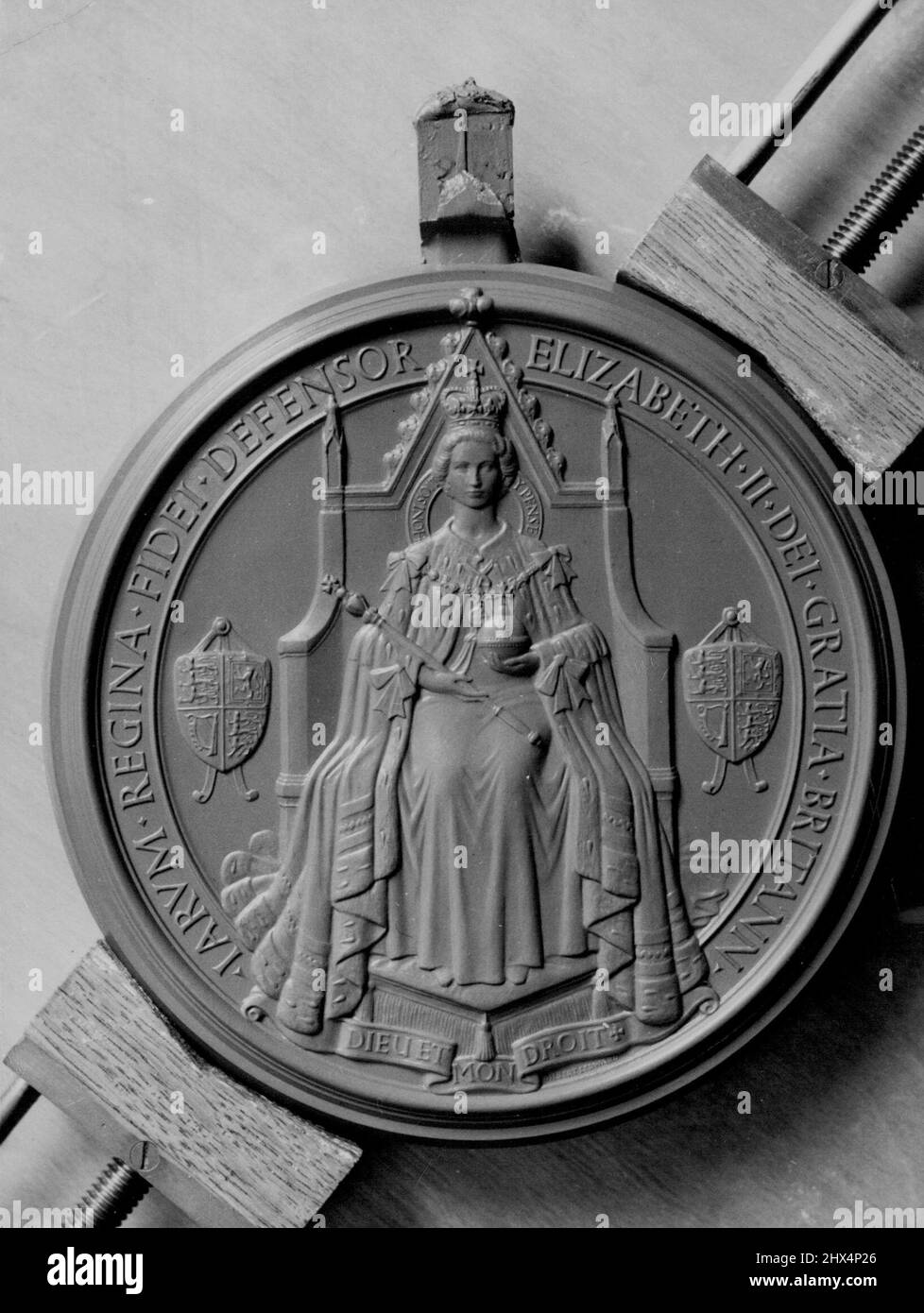 Il rovescio del Grande Sigillo del regno della Regina Elisabetta II Il rovescio del Grande Sigillo del regno di sua Maestà la Regina Elisabetta II. La regina è mostrata in trono e vesti, tenendo nella sua destra il Soeptre e nella sua sinistra, l'Orb. Sotto lo sgabello si trova la leggenda 'Dieu et Mon driot', e parte del motto 'Hani soit qui Mal Y Panse' appare sulla sedia dietro le spalle della regina. Gilbert Ledward, R.A., ha progettato sia l'inverso che l'inverso del Grande Sigillo. Agosto 1, 1953. (Foto dell'Ufficio Centrale dell'informazione). Foto Stock