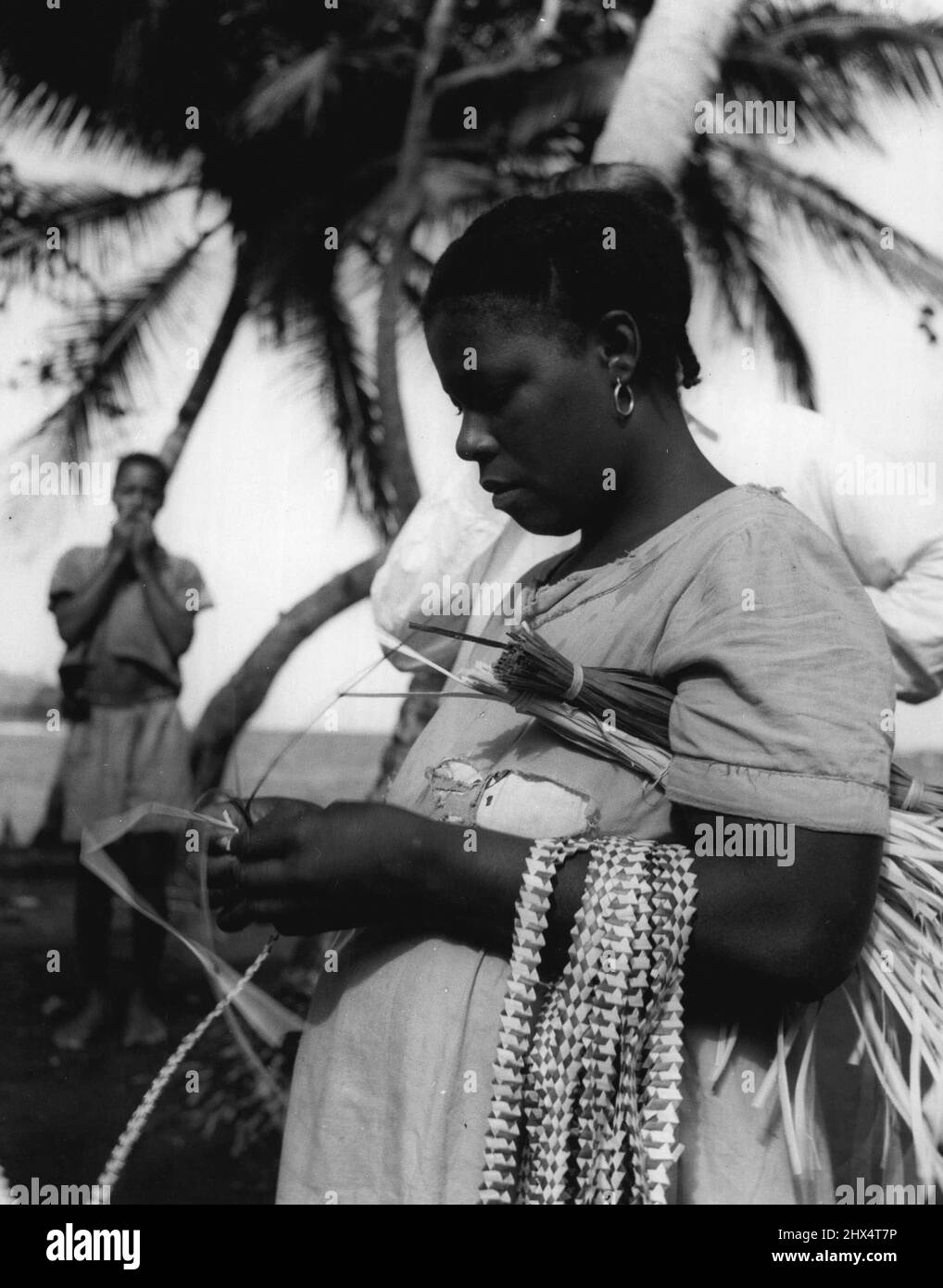 Le dita occupate di Grenada tengono fuori il Sole. Le loro dita lavorano con estrema rapidità intrecciando le strisce di pino selvatico, solitamente in due colori. Luglio 11, 1951. (Foto dell'Ufficio Centrale delle informazioni). Foto Stock