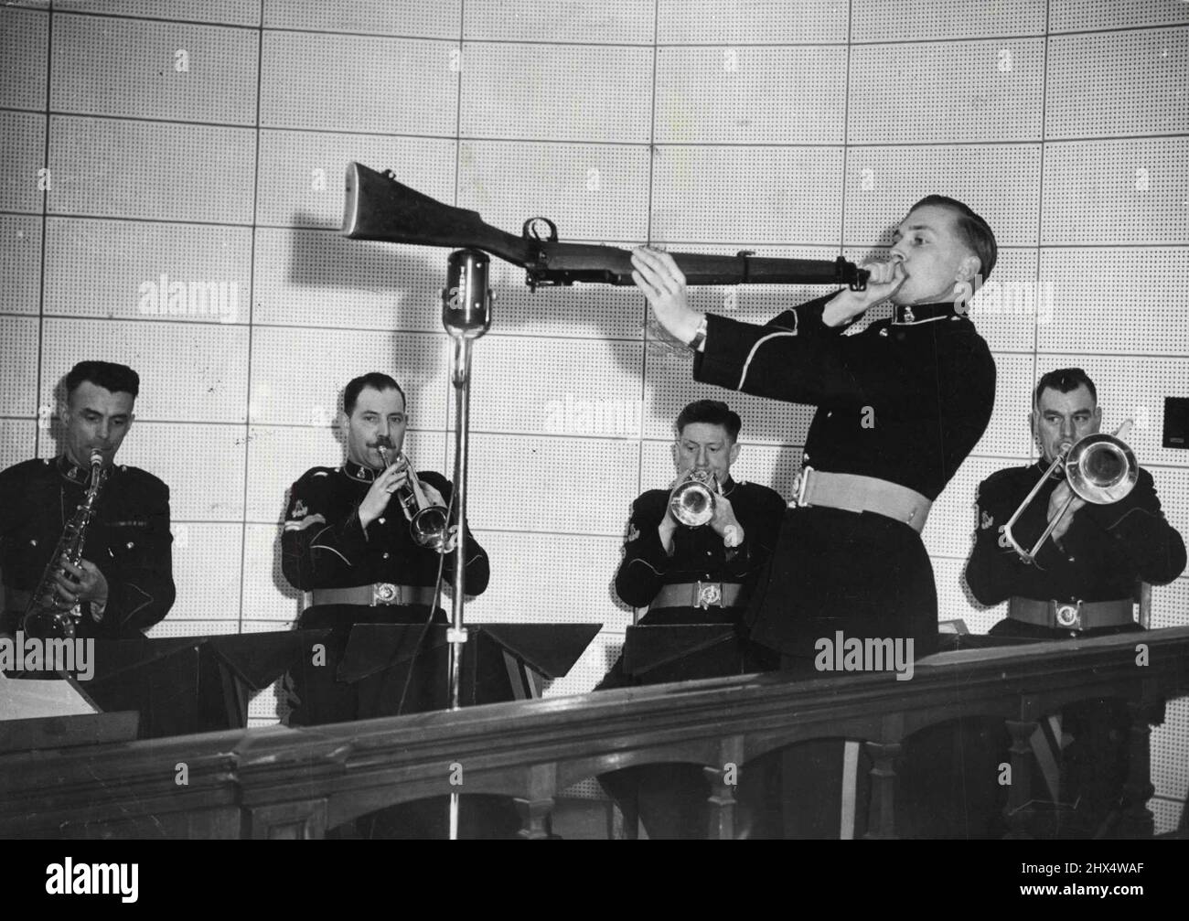 Soffiando la sua cima -- facendo un disperato tentativo di ottenere quel fucile pulito? No. Bandsman John Pelling, della Royal Military Academy Band a Sandhurst, suona il suo fucile come una tromba. Marzo 30, 1954. (Foto per foto del contratto della posta giornaliera). Foto Stock