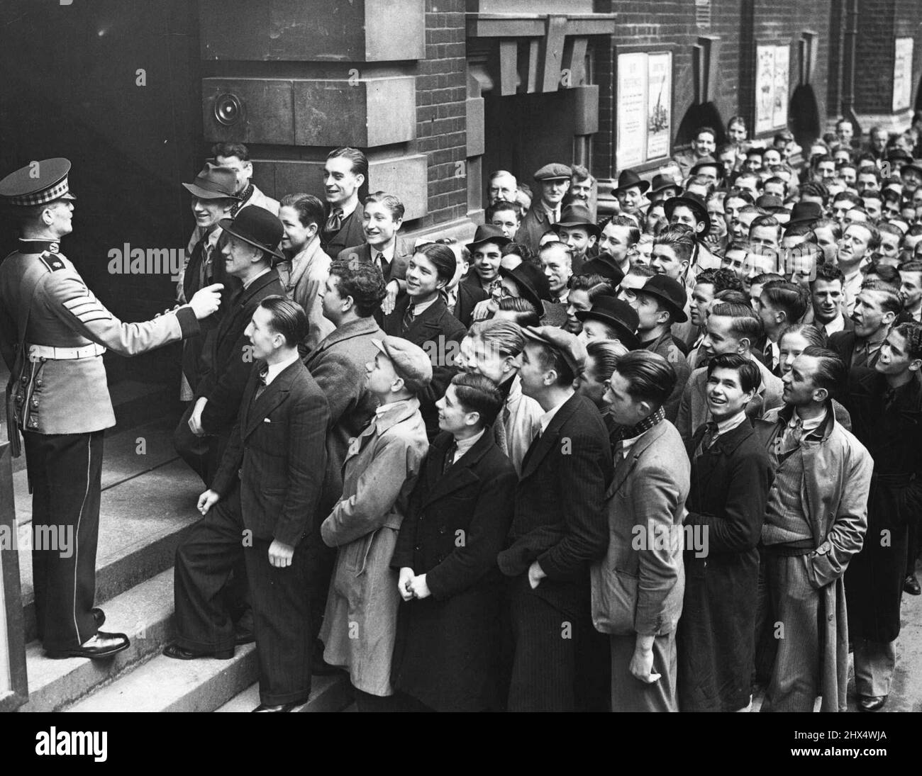 ***** -- la folla di giovani reclute chattando per reclutare sergente mentre aspetta di entrare nell'ufficio. Nonostante il disegno di legge di Iscrizione e la grande unità di reclutamento territoriale, c'è stata una grande corsa di giovani reclute regolari Armata al centro di reclutamento ***** depot, New Scotland Yard, questa mattina. Maggio 22, 1939. (Foto di London News Agency Photos Ltd.). Foto Stock