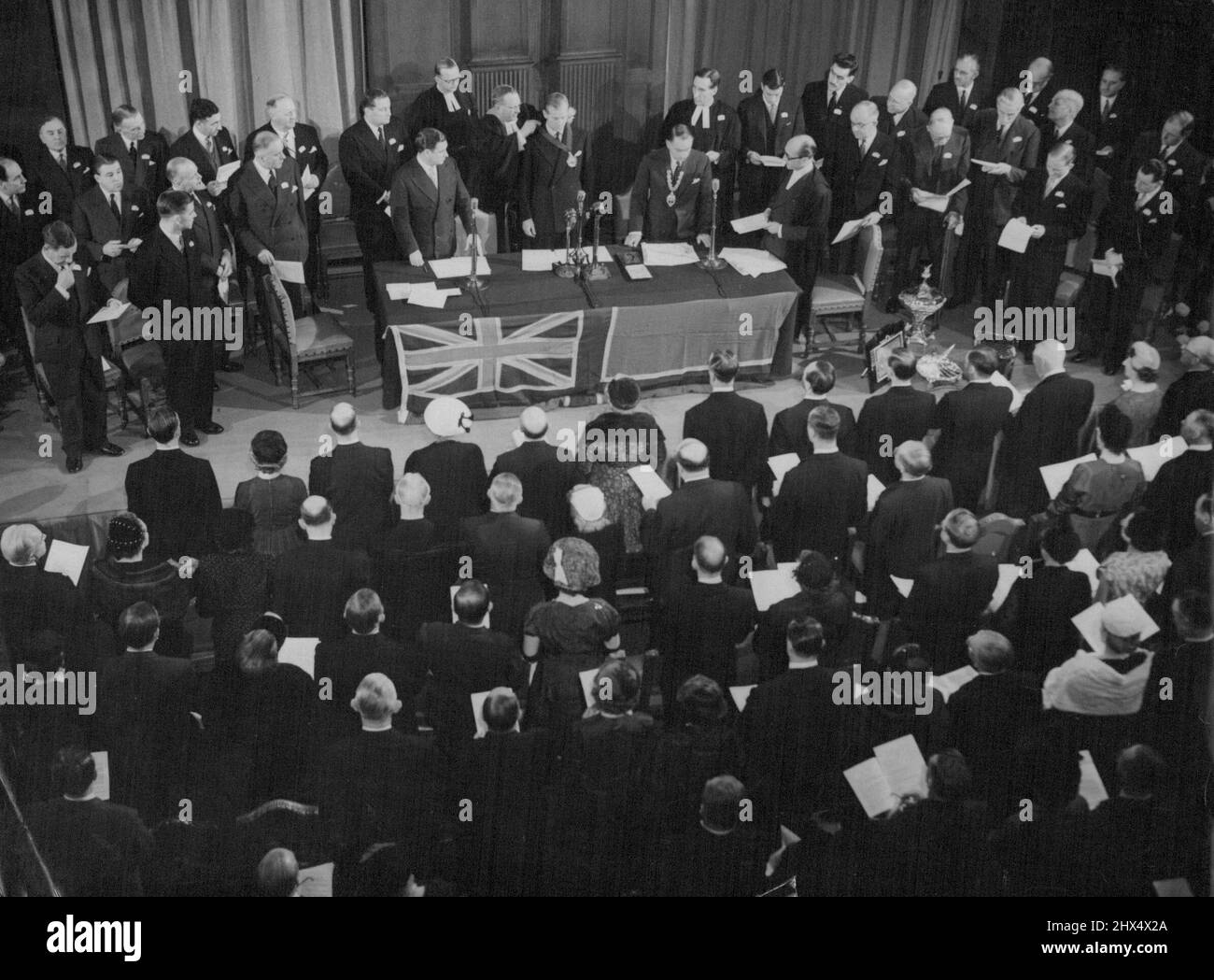Il Duca diventa Gran Maestro di Air Pilots il Duca di Edimburgo, visto al centro del tavolo, è installato come Gran Maestro. Investendolo con badge di ufficio è l'on. Chaplain della Gilda, il Rev, Leslie Wright, Cre, ma. Il Duca di Edimburgo fu installato come Gran Maestro della Gilda dei piloti d'aria e dei navigatori d'aria dell'Impero britannico in una cerimonia impressionante alla sala dei generi alimentari, Londra, E.C. fino a notte (Giovedi). La Gilda è stata fondata nel 1929 sulle linee delle Gilde della città vecchia. I suoi obiettivi principali sono quello di promuovere l'efficienza del volo mercantile e di sostenere la dignità e il prestigio dell'aria Foto Stock
