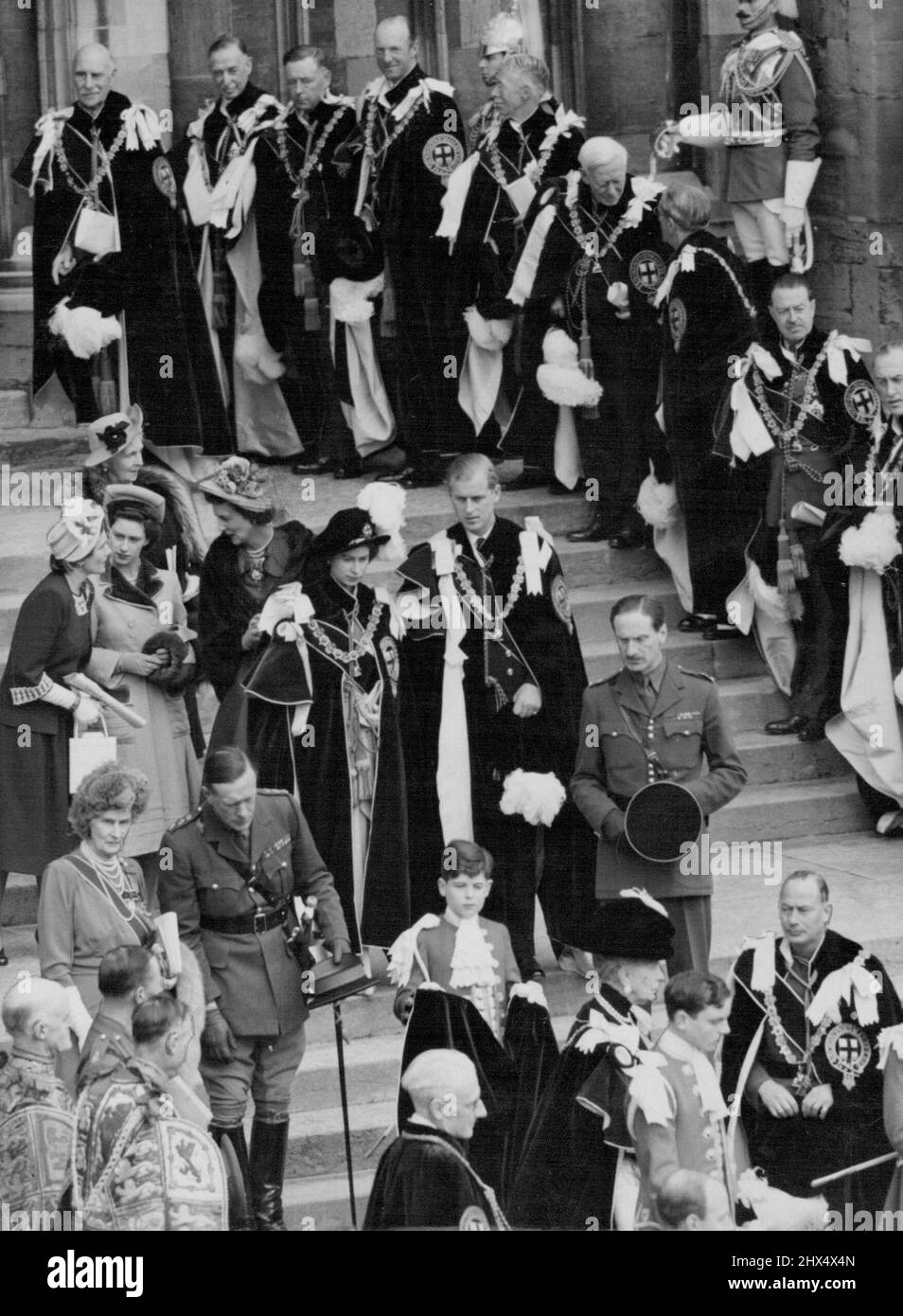 La principessa e il duca lasciano St. George -- sua altezza reale la principessa Elisabetta e suo marito, il duca di Edimburgo, hanno vagato come cavalieri del garter, visto lasciare la cappella di St. George dopo la cerimonia oggi 23 aprile. In fondo alla foto si trova la Regina Maria scortata dal Duca di Gloucester (a destra). Dietro la principessa Elisabetta si trovano (da sinistra a destra) la duchessa di Gloucester, la principessa Margaret e la duchessa di Kent. Tra i Cavalieri che fiancheggiano i gradini ci sono il Conte di Athlone (in alto a sinistra); il Duca di Norfolk (terzo da sinistra); e il Visconte Maresciallo di campo Alexander (estrema destra). Una brillante cerimonia ha preso plac Foto Stock
