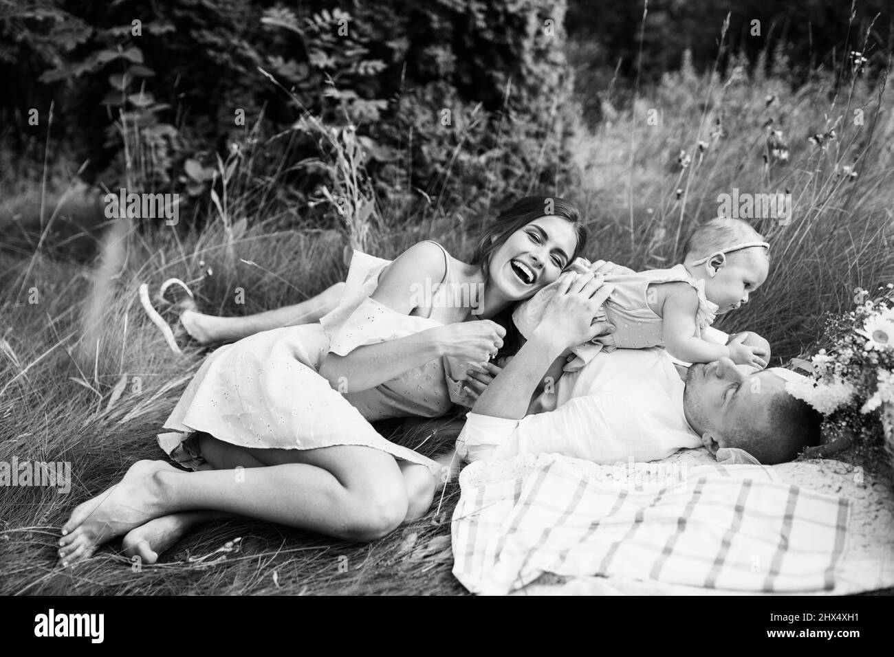 I genitori erano molto contenti con una figlia adorabile che si rilassava in coperta al parco, sorridendo, abbracciando, con una bella famiglia che si era fatto un picnic in estate, con un paterno che si preoccupava Foto Stock