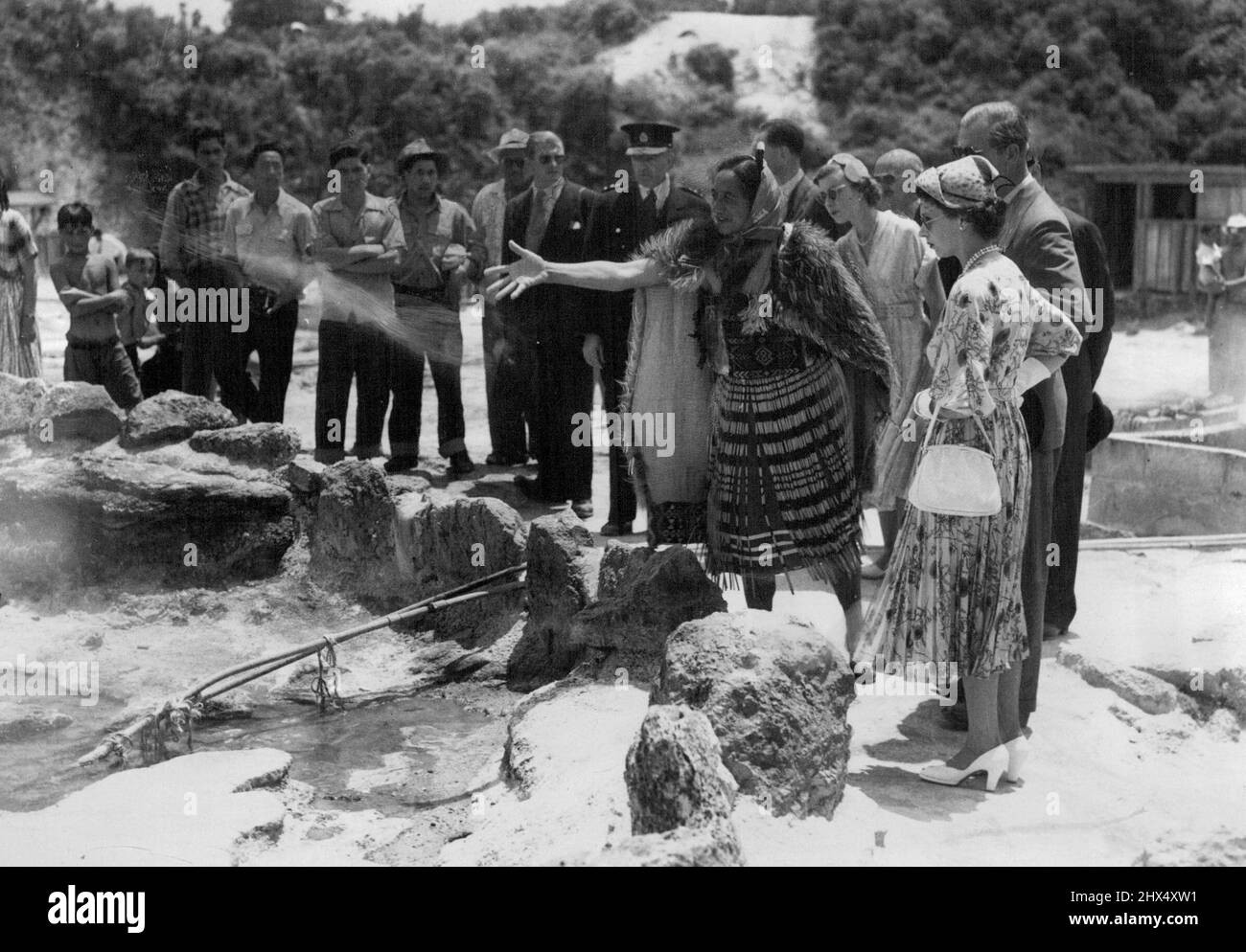 Rangi, famosa Guida Maori, gettando terra nella primavera Champagne. Si tratta di acqua bollente e la terra la fa più bolla, la Regina e il Duca stanno guardando. Bolle - poi venire il tour di Rotorua 'hot' aree. Rangi, la famosa guida Maori, getta terra sulla Champagne Spring per fare l'acqua bollente e il fango bolle di più. La coppia reale è stata affascinata dalla regione termale di fama mondiale. Gennaio 11, 1954. Foto Stock