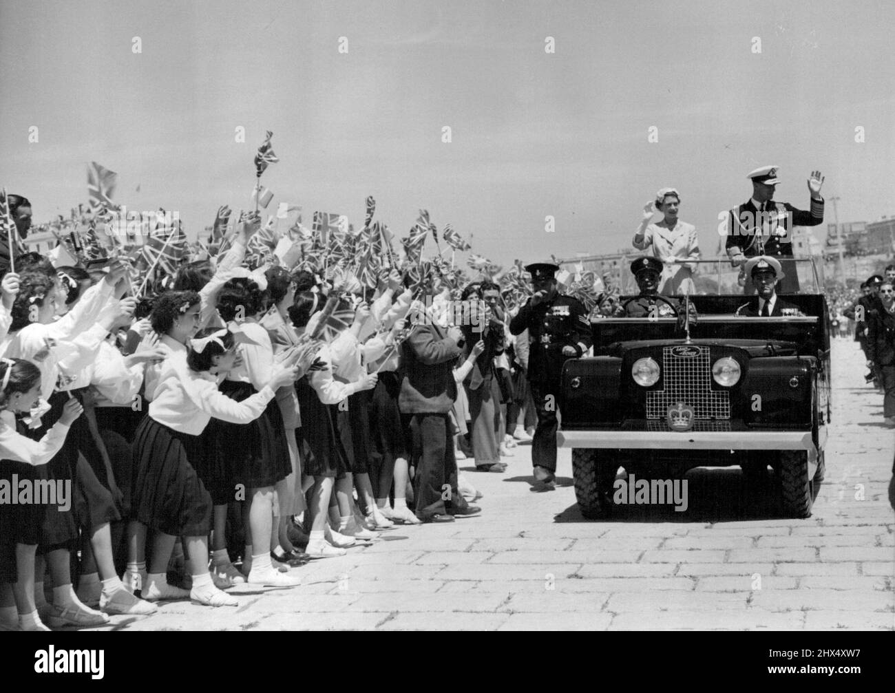 La Regina a Malta un'accoglienza eccezionale da 14.000 bambini. H. M, la Regina e S.R.H. il Duca di Edimburgo, alzandosi in piedi in una Land Rover, sorridono e ondano in riconoscimento, come 14.000 bambini acclamano lusinghiero, all'accompagnamento di sbattenti Union Jacks, come accolgono la coppia reale in un Rally per bambini della Scuola a Floriana, Malta, G. C. oggi. Maggio 3, 1954. (Foto di Fox Photos). Foto Stock