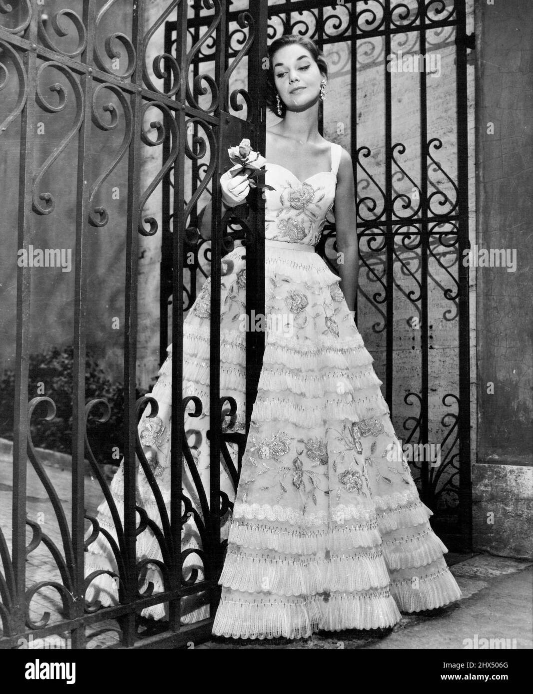 Prendendo le curve -- c'è romanticismo e grazia femminile in questa serata abito da Fontana Sisters di Roma, tipica delle offerte di stilisti italiani, che hanno accettato di mantenere le curve femminili in modo questo autunno, la palla abito è fatto in rete bianca su mango taffeta. La gonna completa e il corpetto modellato sono ricamati sontuosamente con paillettes, pietre semi-preziose e filo metallico, con fasce di pizzo che circondano la gonna. Agosto 05, 1955. (Foto di United Press Photo) Foto Stock