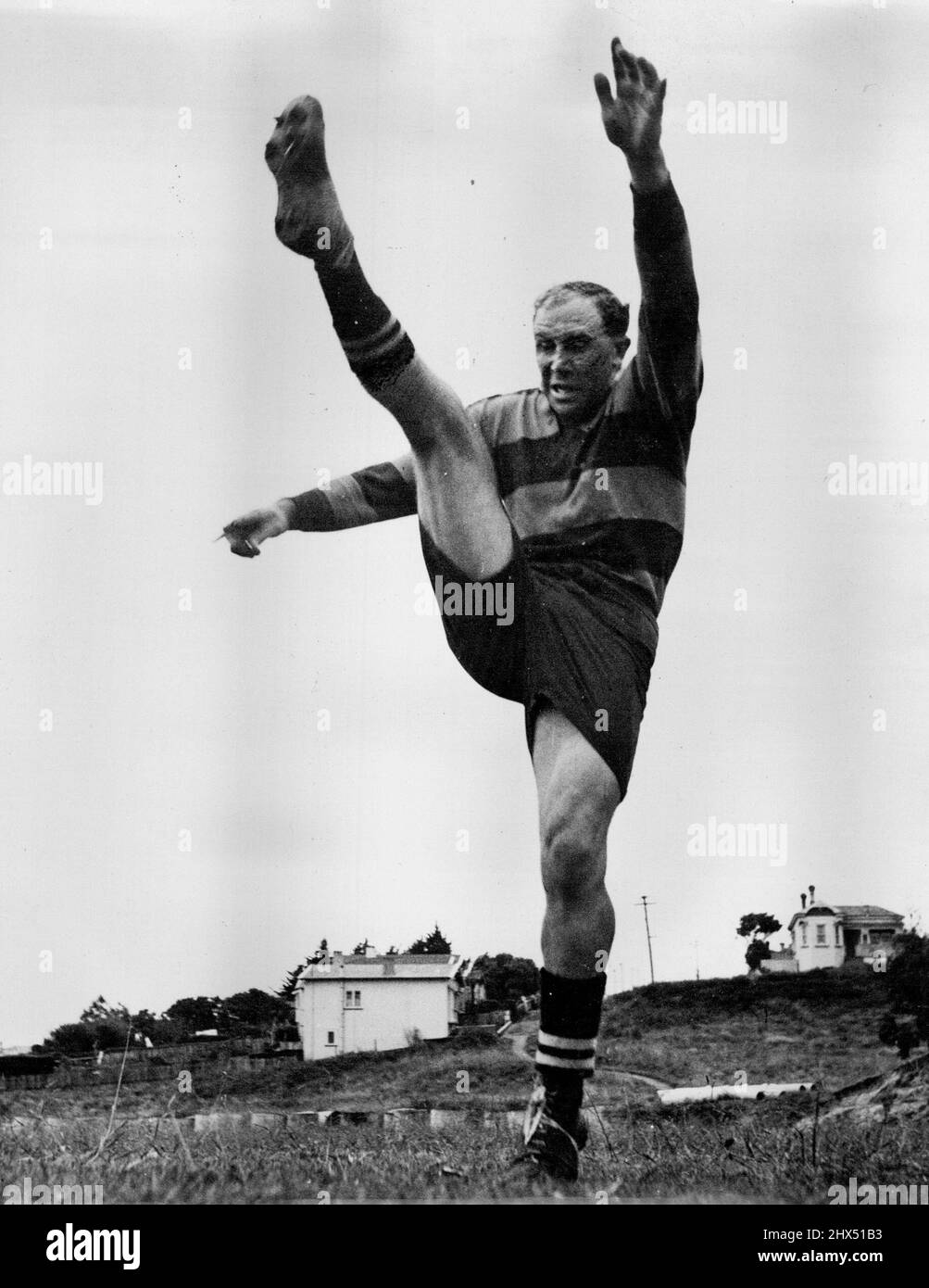 Alla luce grigia dell'alba Bob Scott si impigorì la gamba in preparazione all'avvicinarsi della stagione di rugby del 1948 ad Auckland. Anche se è molto fortemente costruito è flessibile come un ballerino ballerino ballerino/come questa immagine mostra. Indossa la sua maglia Ponsonby Club. Luglio 13, 1951. Foto Stock