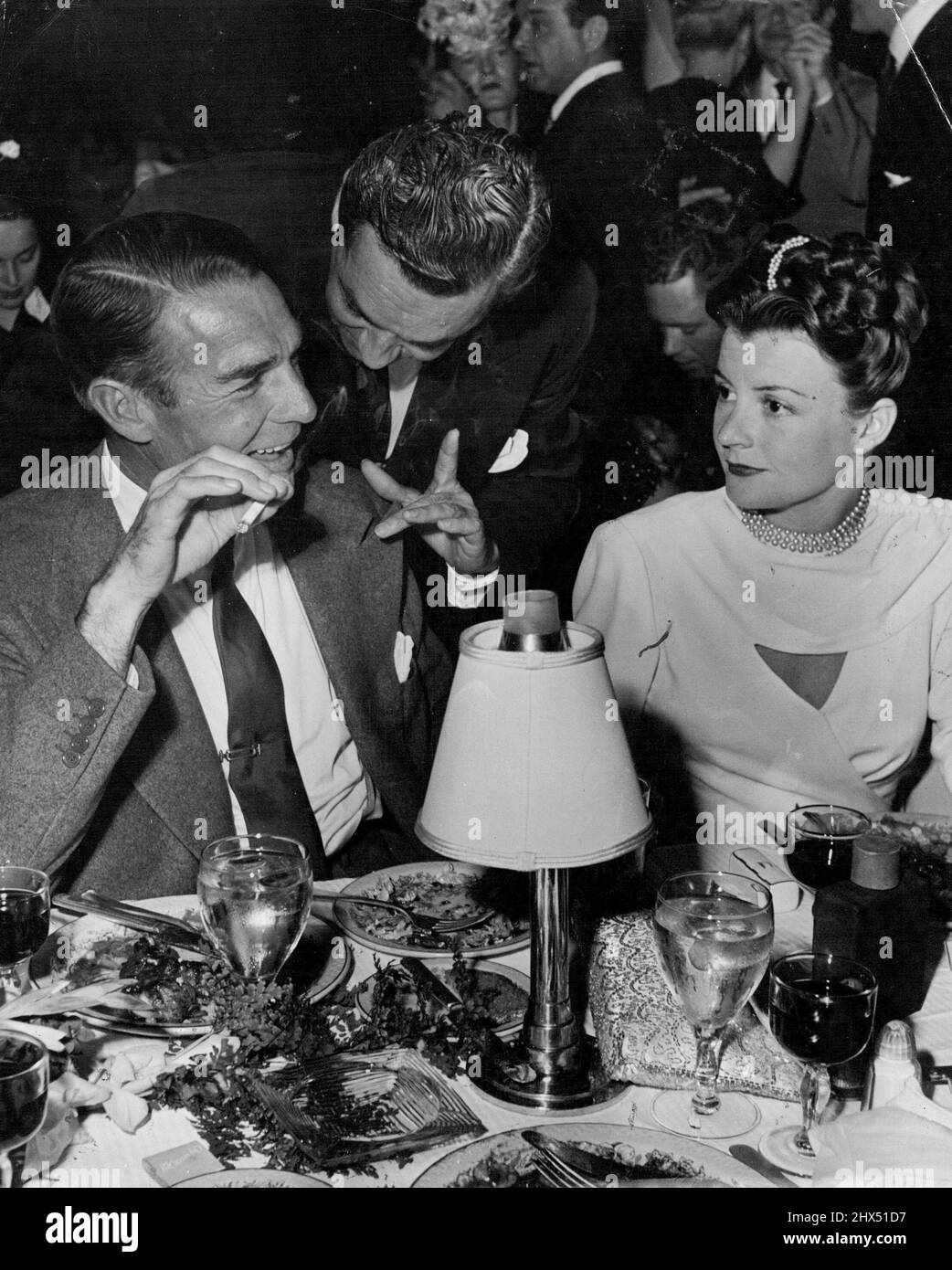 Deve essere un certo genere di linguaggio di segno che Arthur Cameron, sposo di Kay Aldrich ed ex hubby di June Knight, sta provando ad ottenere sopra Randy Scott e moglie, Pat Stillman. Settembre 08, 1946. (Foto di Jay Scott). Foto Stock