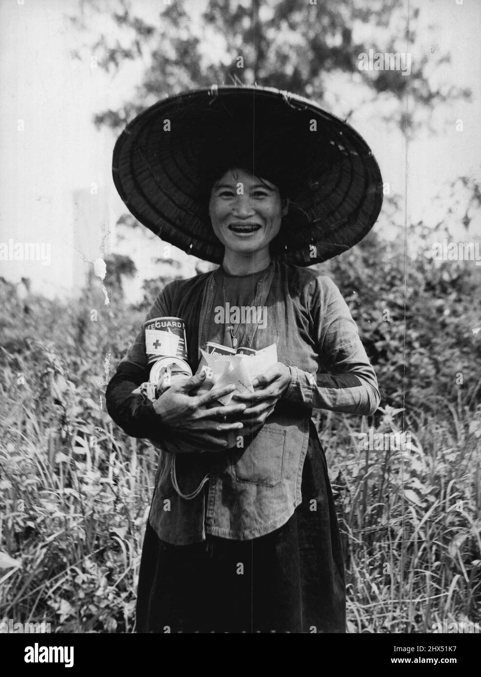 Una donna vietnamita che ha appena ricevuto la sua razione. Notare le etichette che annunciano che sono un regalo dalla Croce Rossa Australiana. Dicembre 11, 1954. Foto Stock